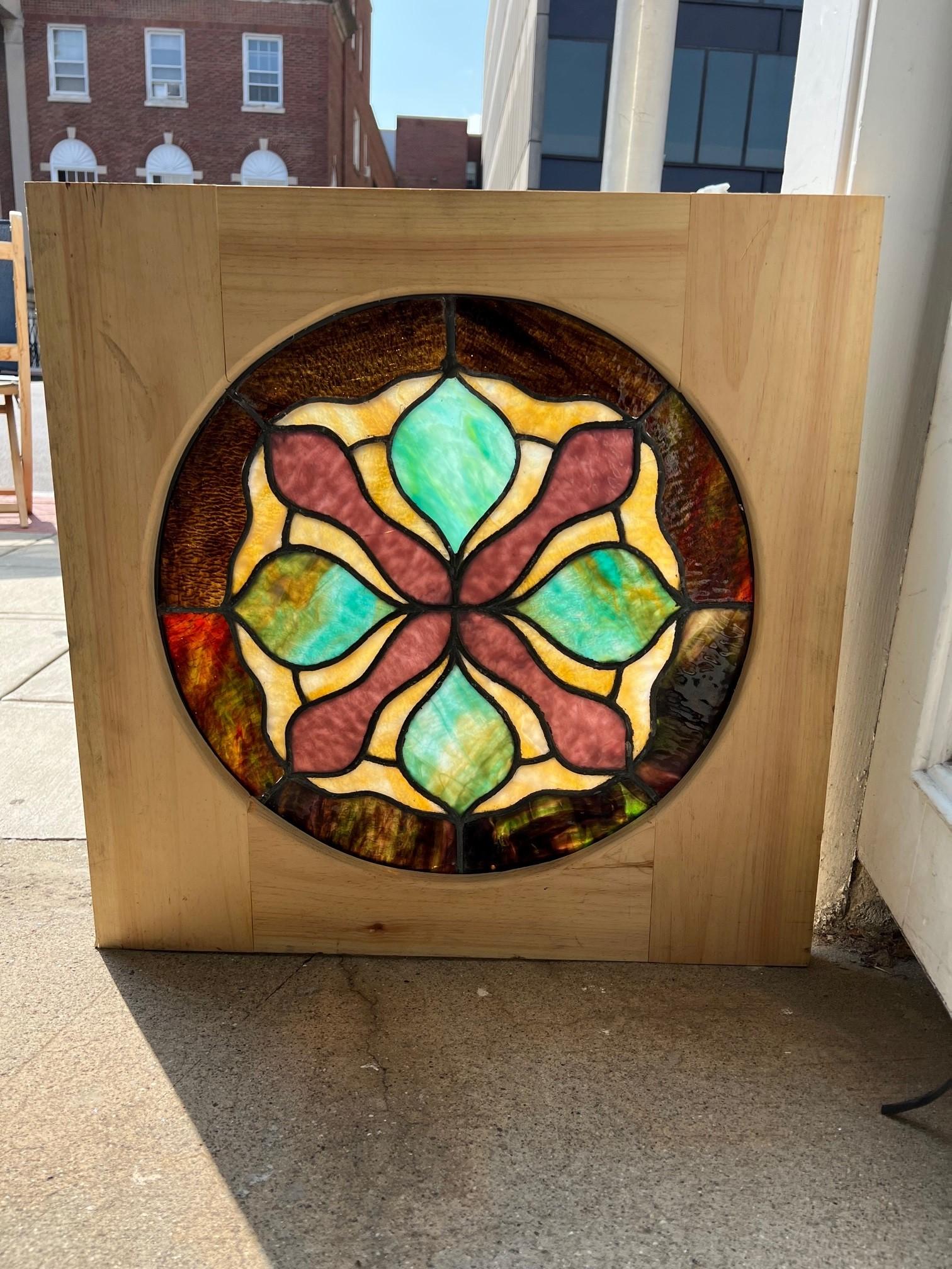 Early 20th Century antique round stained glass window in a new wood frame. This is a nice round stained glass window which are harder to find and a great size. The colors are beautiful and in good condition, it has a crack shown in the photos but is