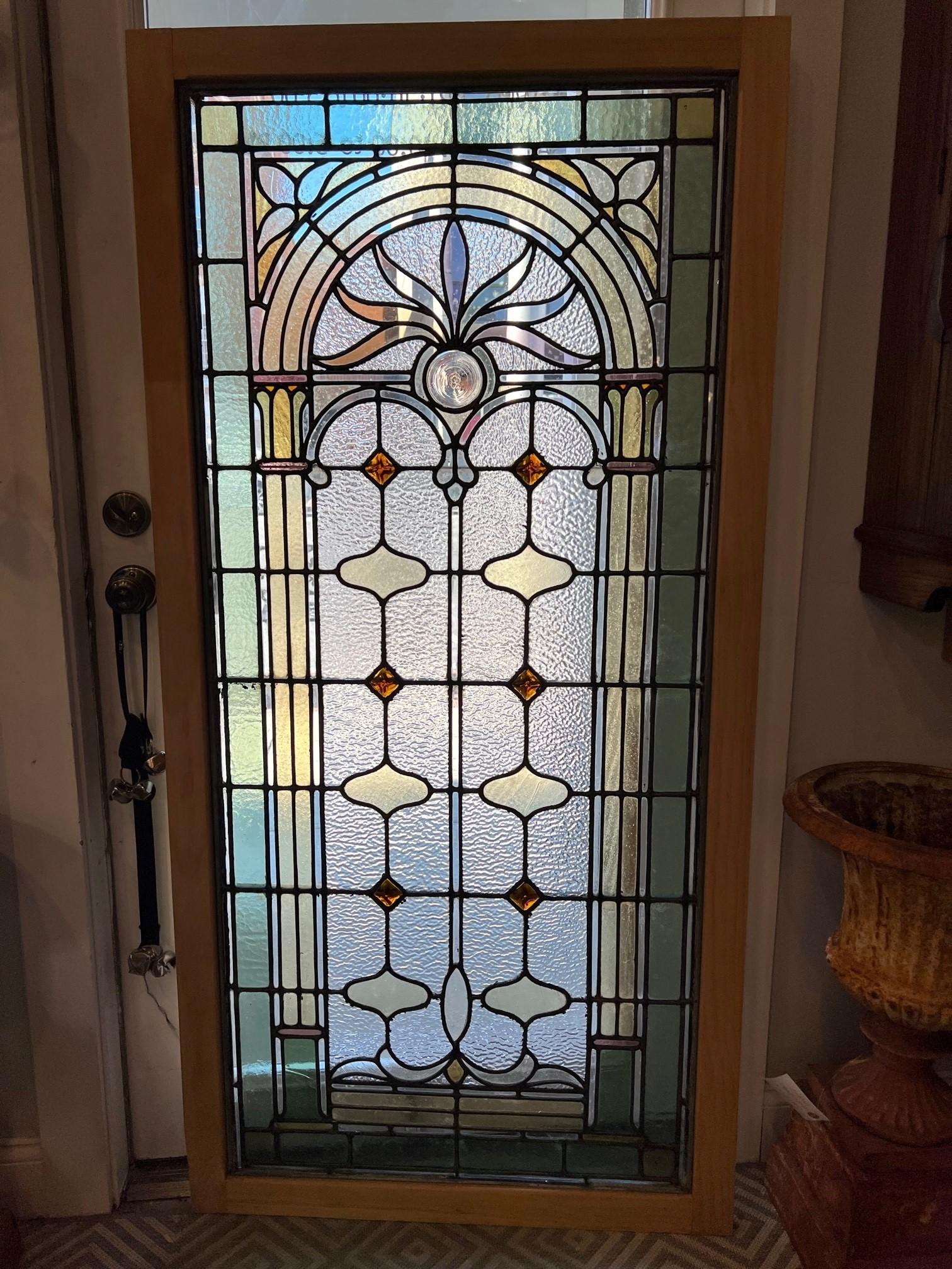Early 20th century stained glass window in a new frame in great condition. This is a beautiful window with an arch top in the design and a rondel in the center. In the light it is a nice bright window with great colors. This is one of many windows