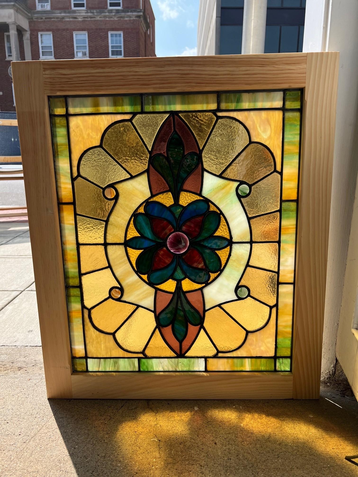 Early 20th Century antique stained glass window in a new wood frame. Salvaged from a building in Pittsburgh Pa, the original frame was rotten and replaced with a new wood frame. It has great colors, nice and bright with a purple swirl center jewel.