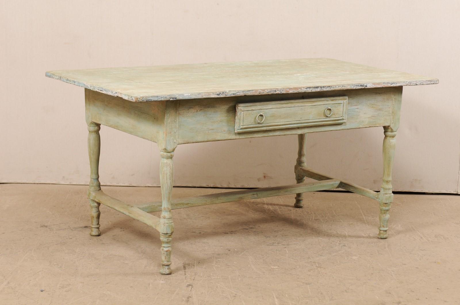 A Swedish painted wood table with single drawer from the early 20th century. This antique table from Sweden has a rectangular-shaped top that overhangs the plain, yet deep skirt beneath which houses a centre of one of the longer sides. It is raised