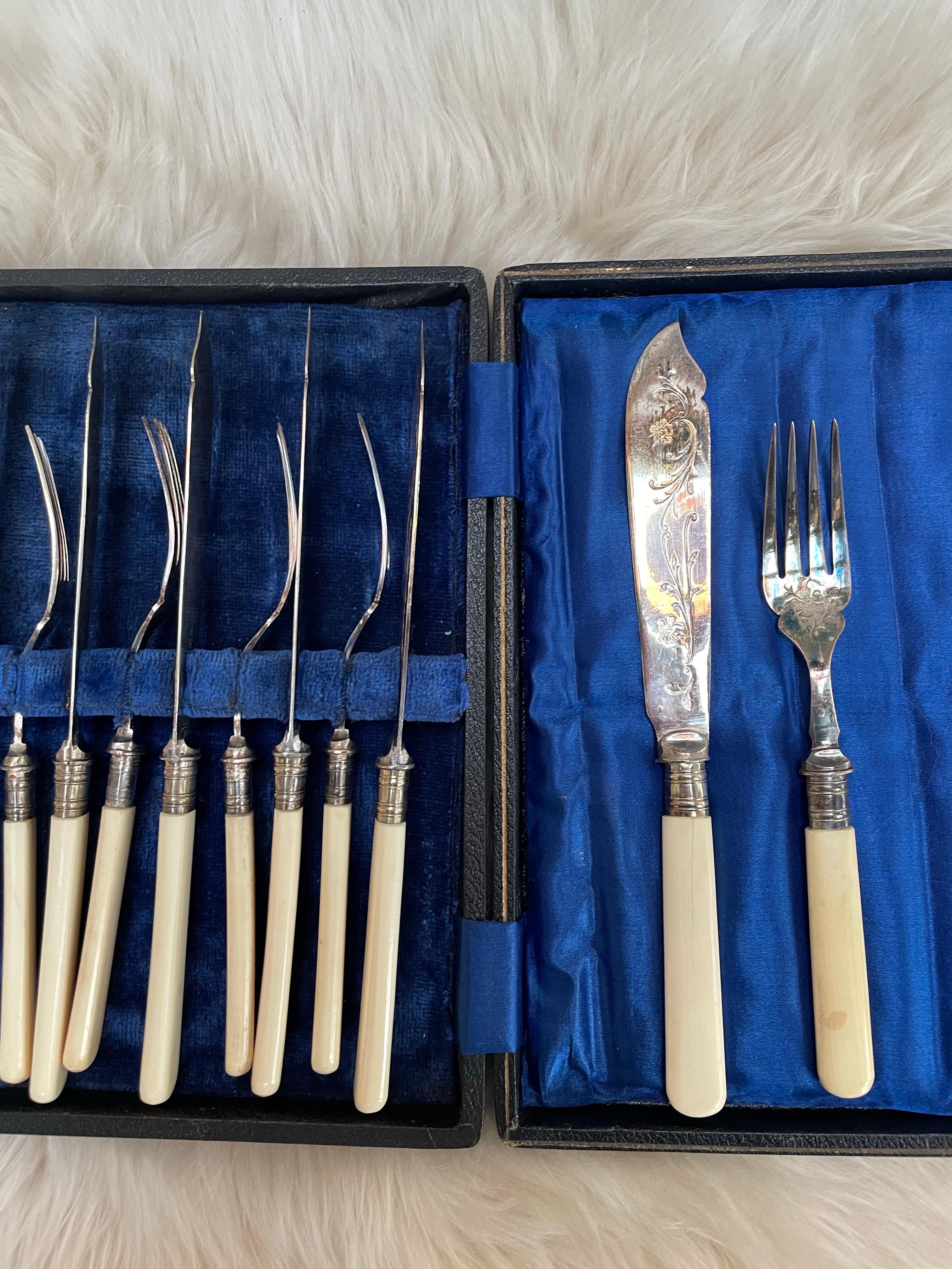 
An elegant early 20th-century English fish service for six, featuring engraved silver-plated blades and tines paired with smooth, polished bone handles. Each piece is finely detailed with scrolling floral motifs, demonstrating the refined