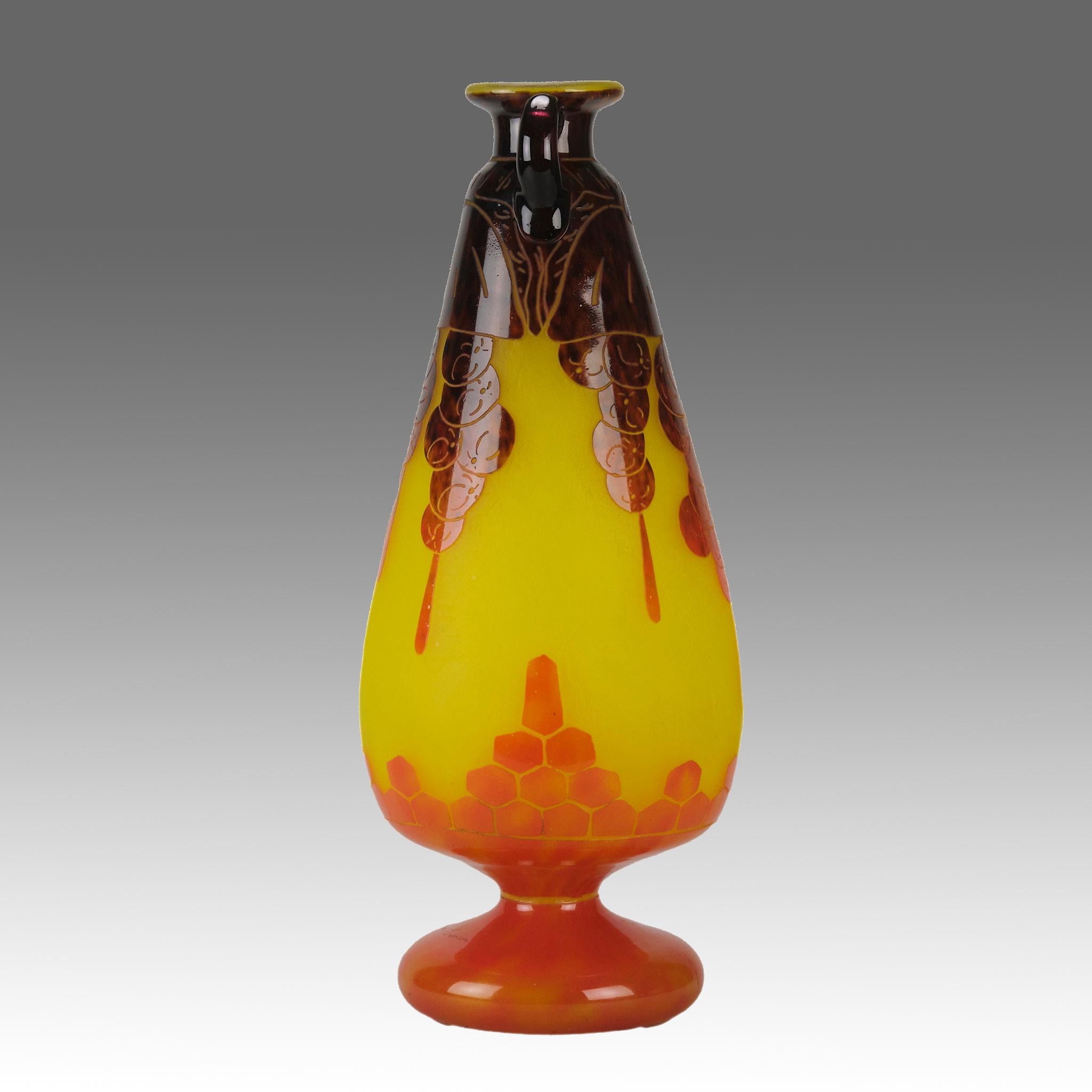 Un étonnant vase en verre Art déco du début du 20e siècle, dont le sommet est gravé de fleurs suspendues d'un bordeaux profond et d'un motif de nid d'abeille d'un orange chaud s'élevant du fond sur un champ jaune vibrant. Le vase présente