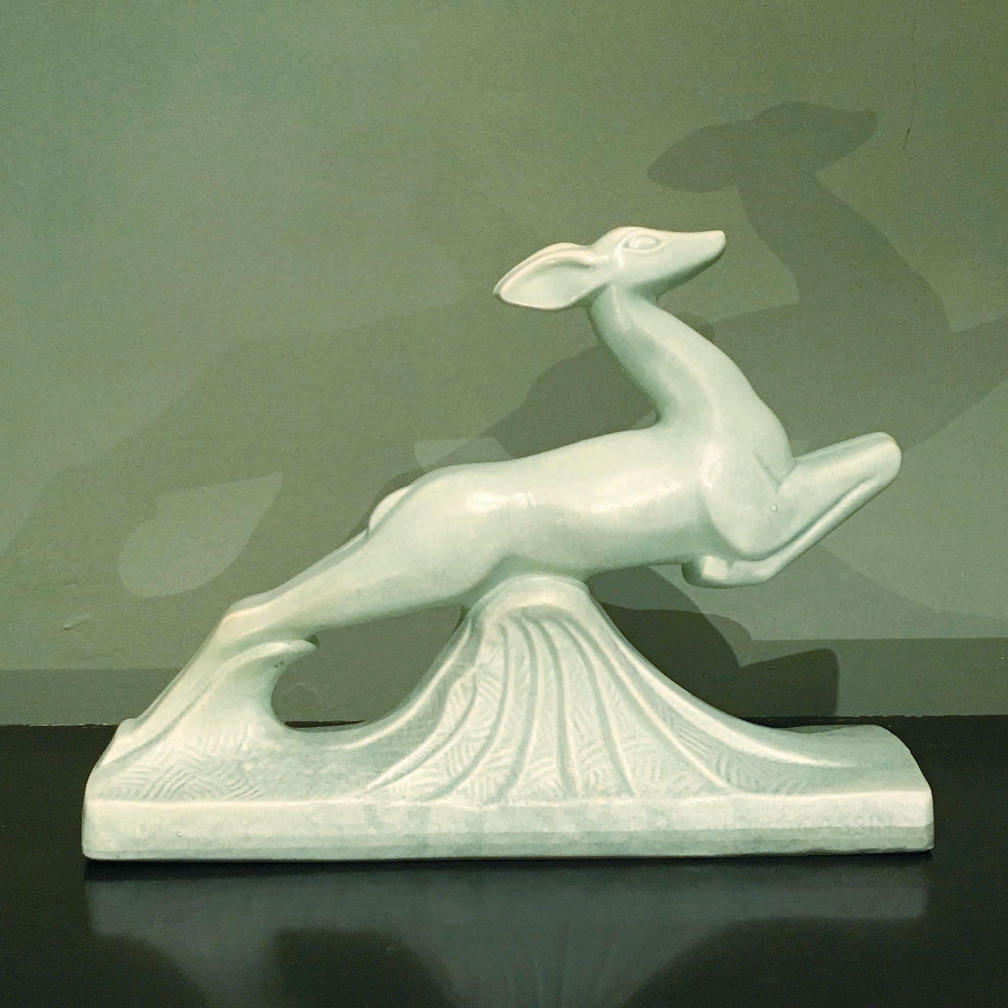 A charming Art Deco light green crackle glazed ceramic figure of a jumping antelope (