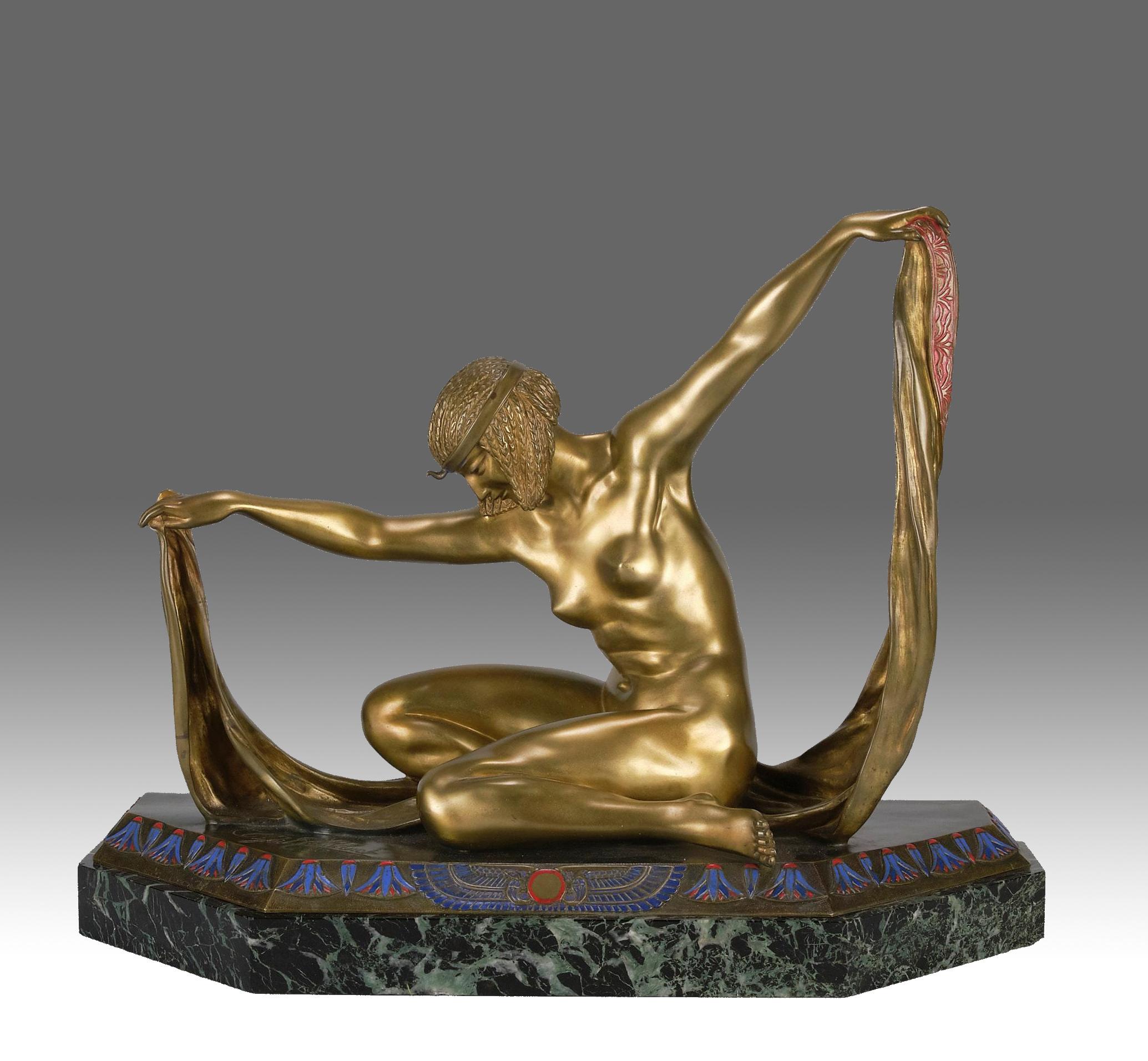 Una squisita figura in bronzo dorato Art Deco francese dell'inizio del XX secolo che raffigura una giovane ballerina seduta su uno scialle che solleva ai suoi lati. La superficie è decorata con un antico disegno egizio dipinto a smalto, con colori e