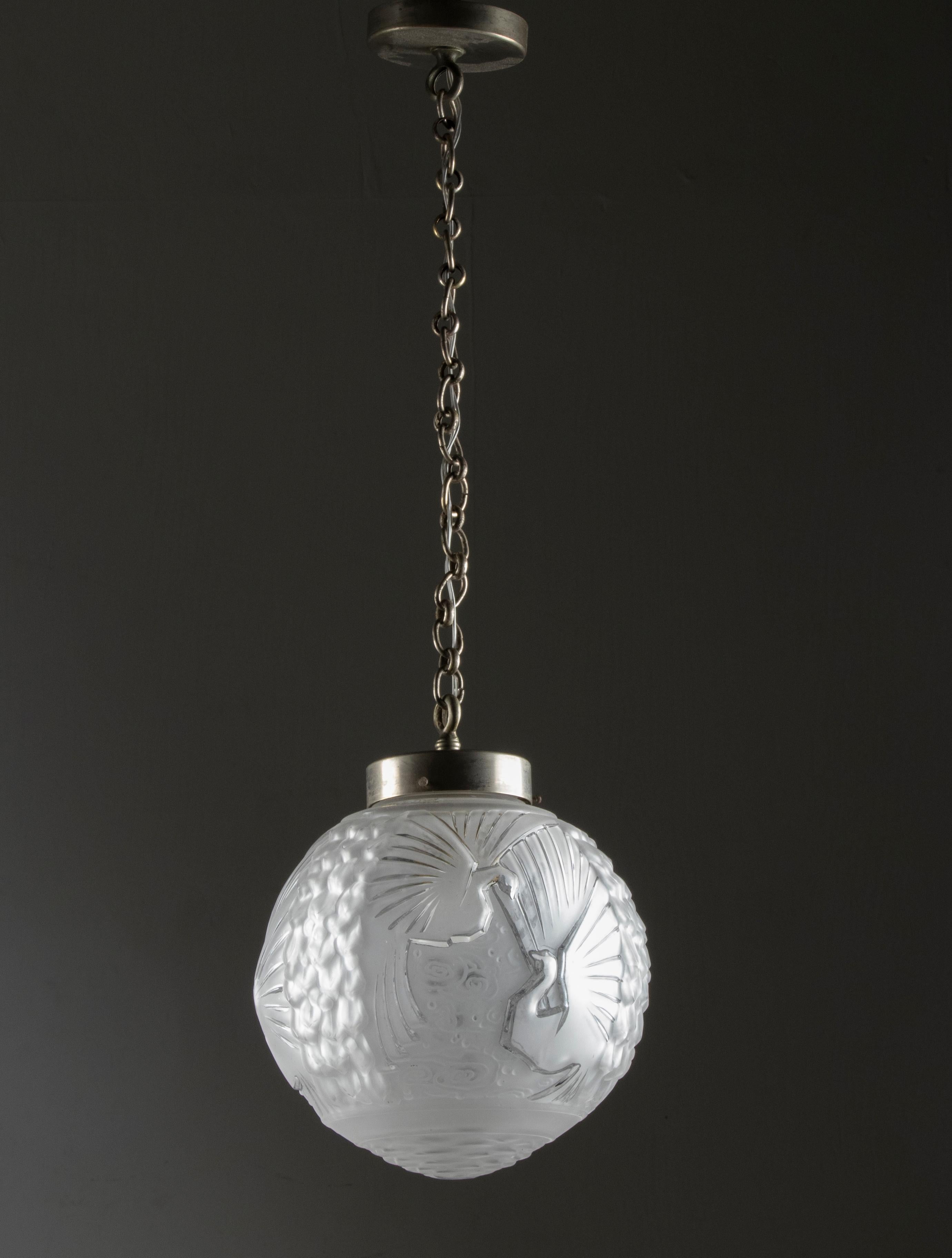 Un'elegante lampada a globo in stile Art Déco di Muller Frères. La galleria del paralume e la catena sono in metallo. Ha un paralume a globo in vetro smerigliato modellato, decorato con uccelli pavone, realizzato da Muller Frères. All'interno di una