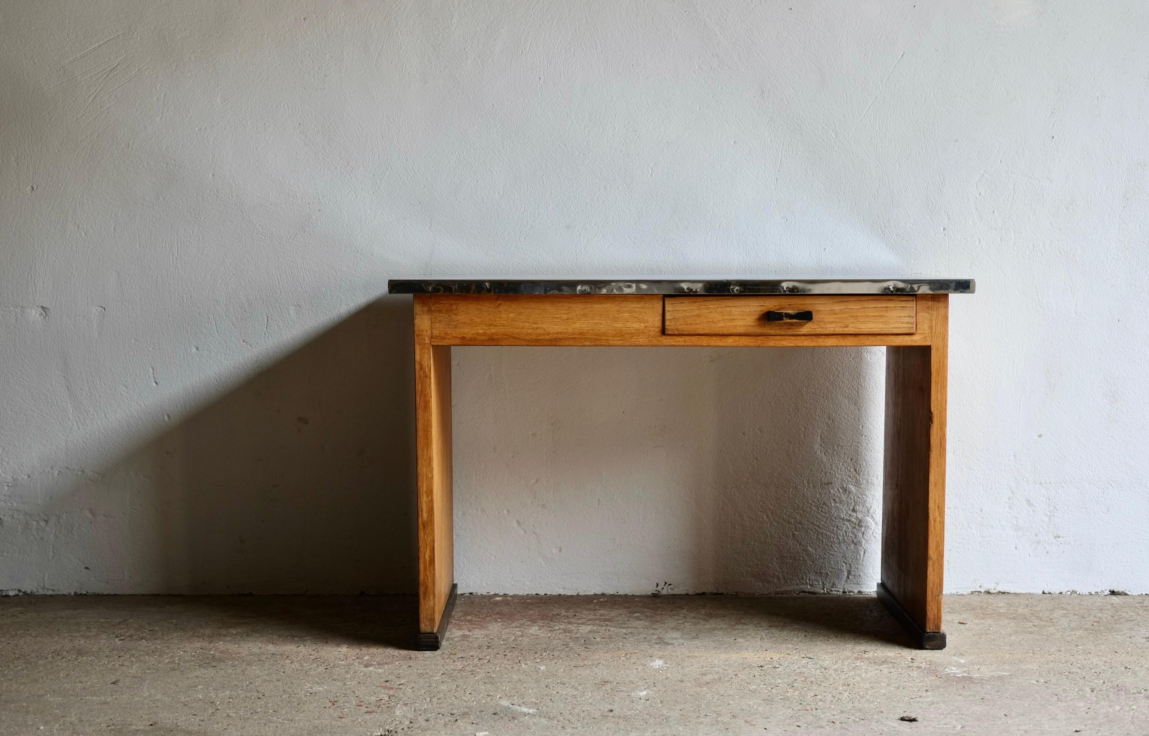 An early 20th century French modernist oak desk featuring a metal clad top and drawer. 

There is a beautiful patina to the desk which portrayed through the worn paintwork on the handle and the markings to the metal top. 

H 75 W 116 D 70.5 cm
