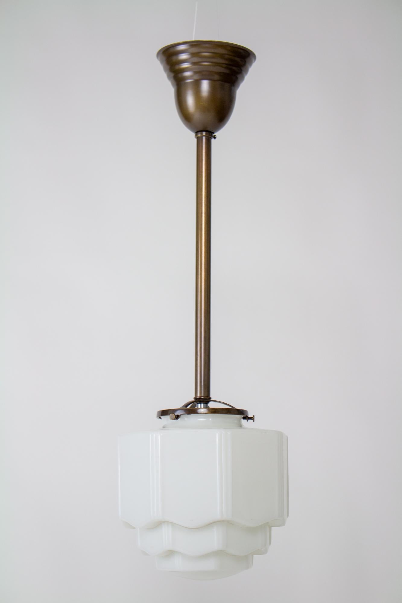 Early 20th century art deco milk glass pole pendant. Brass pole pendant with a dark antique brass finish. Milk glass art deco skyscraper shade. Glass in very good condition. Fixture is custom, in excellent condition, with an even finish, rewired and