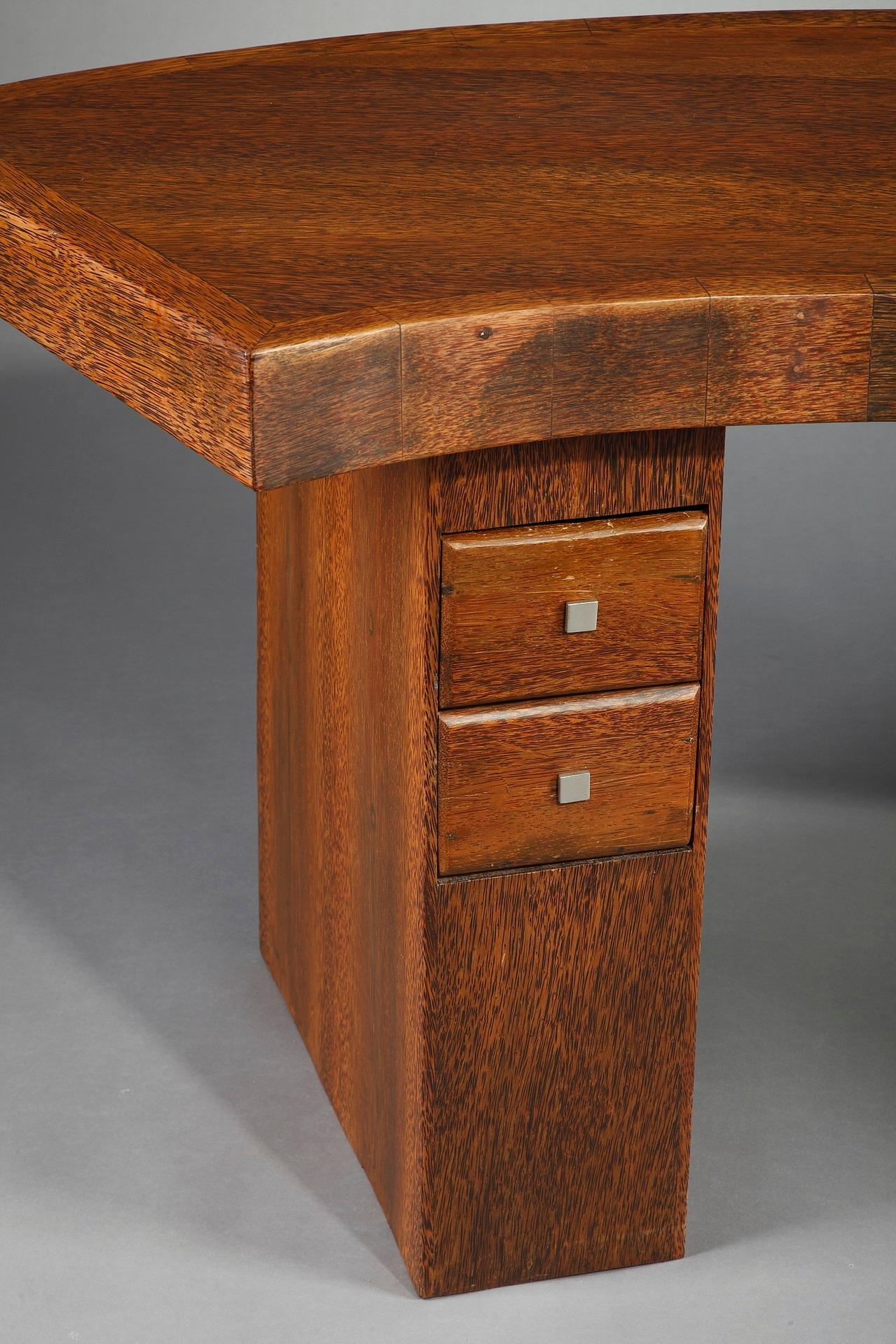 Art Deco writing desk crafted of palmwood. It boasts a large, curved writing surface, resting on two rectangular legs. The desk reveals two small drawers in each leg. This French desk is very elegant in both simplicity and severity of form,

circa