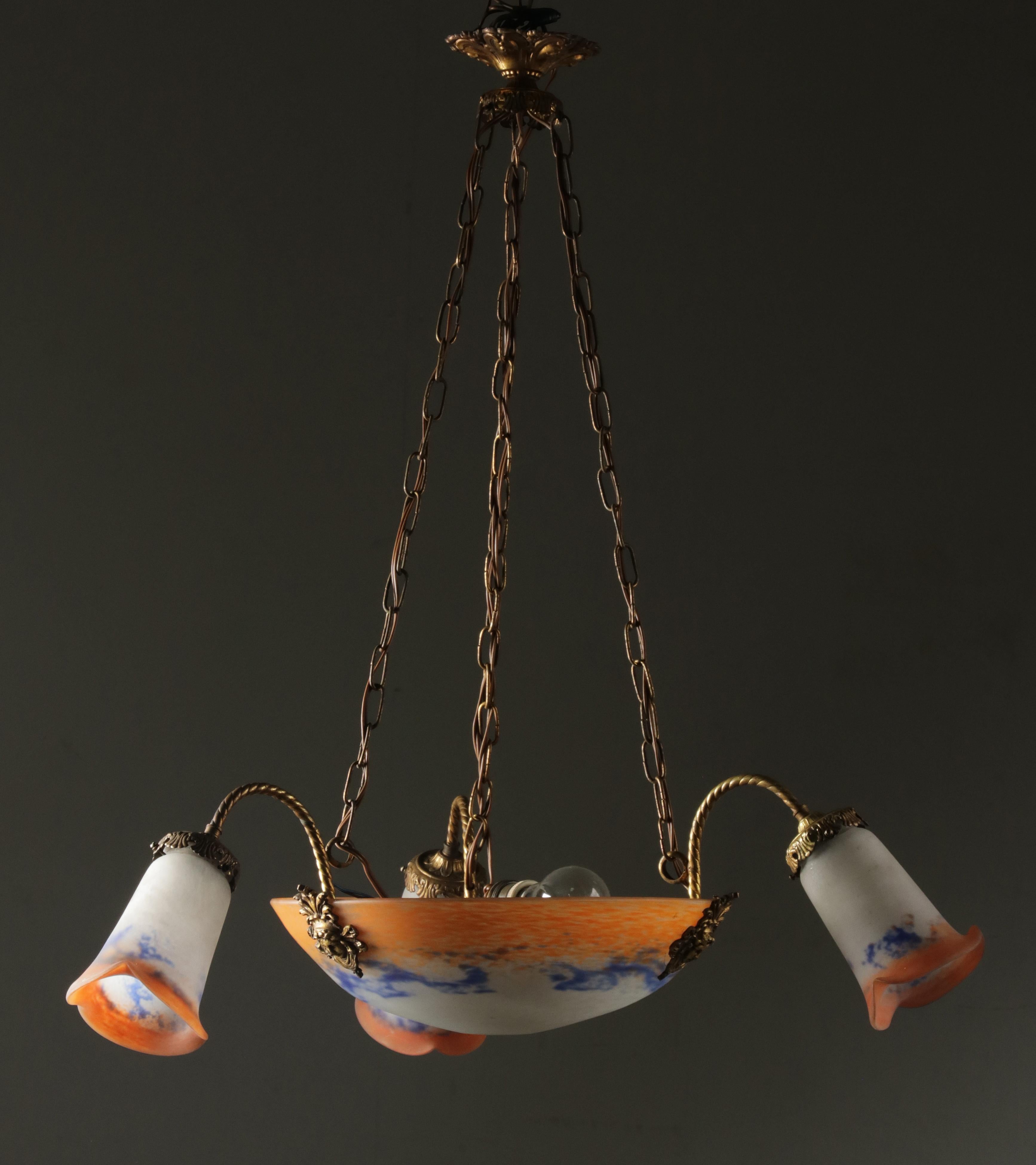 A French Art Deco pendant chandelier by Jean Noverdy, Dijon, France. Made of thick mottled colored paste glass “Pâte de Verre”, signed ”Noverdy France”. The outside fixtures are made of copper. Total four light points (E27 fitting), including the