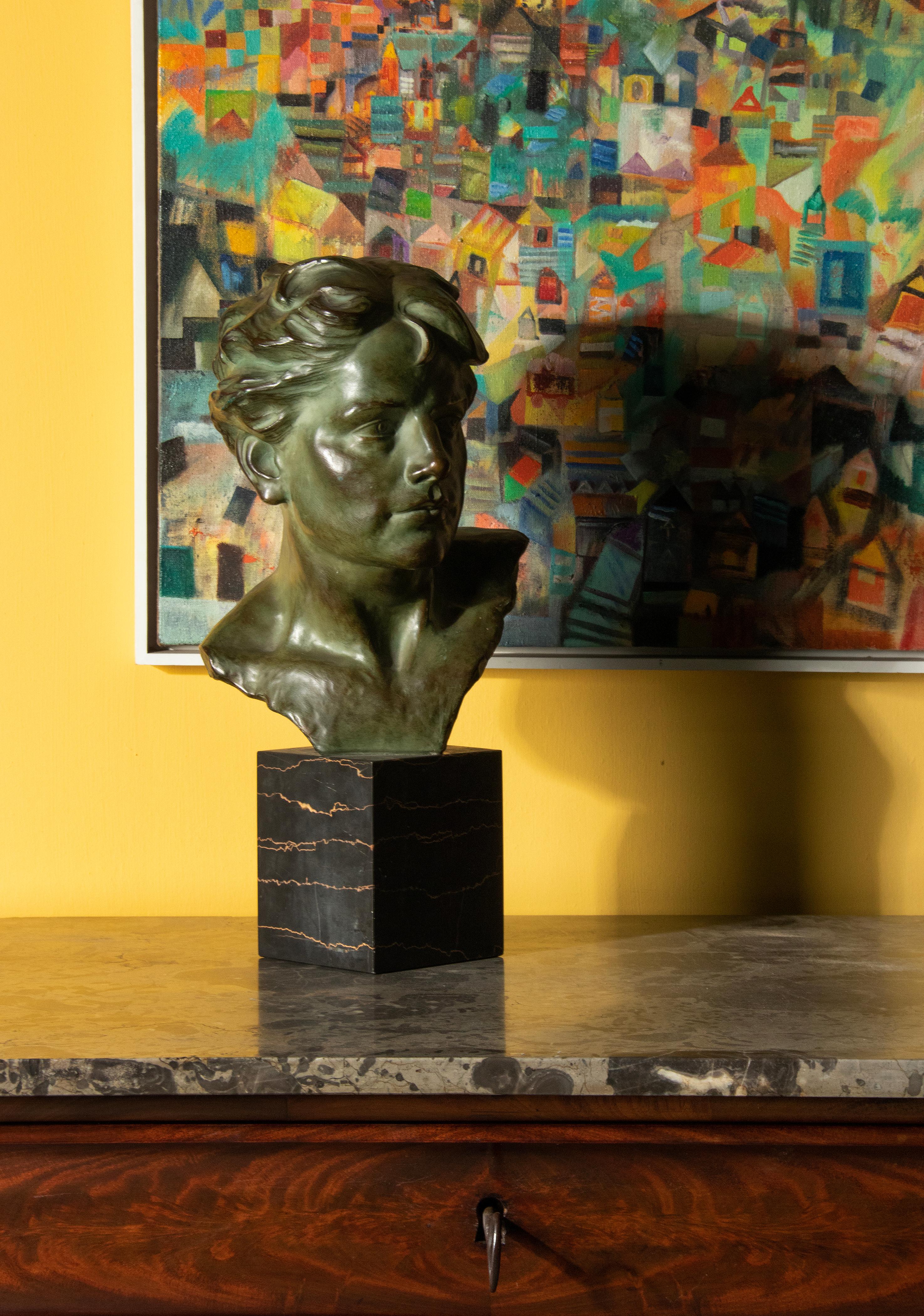 Beautifully expressive sculpture of a young man from the Art Deco period. The bust is made of terracotta with a bronze colored green patina. On a Porto Nero marble pedestal. Signed on the back. Made in Belgium, circa 1920-1930. Made by the Belgium