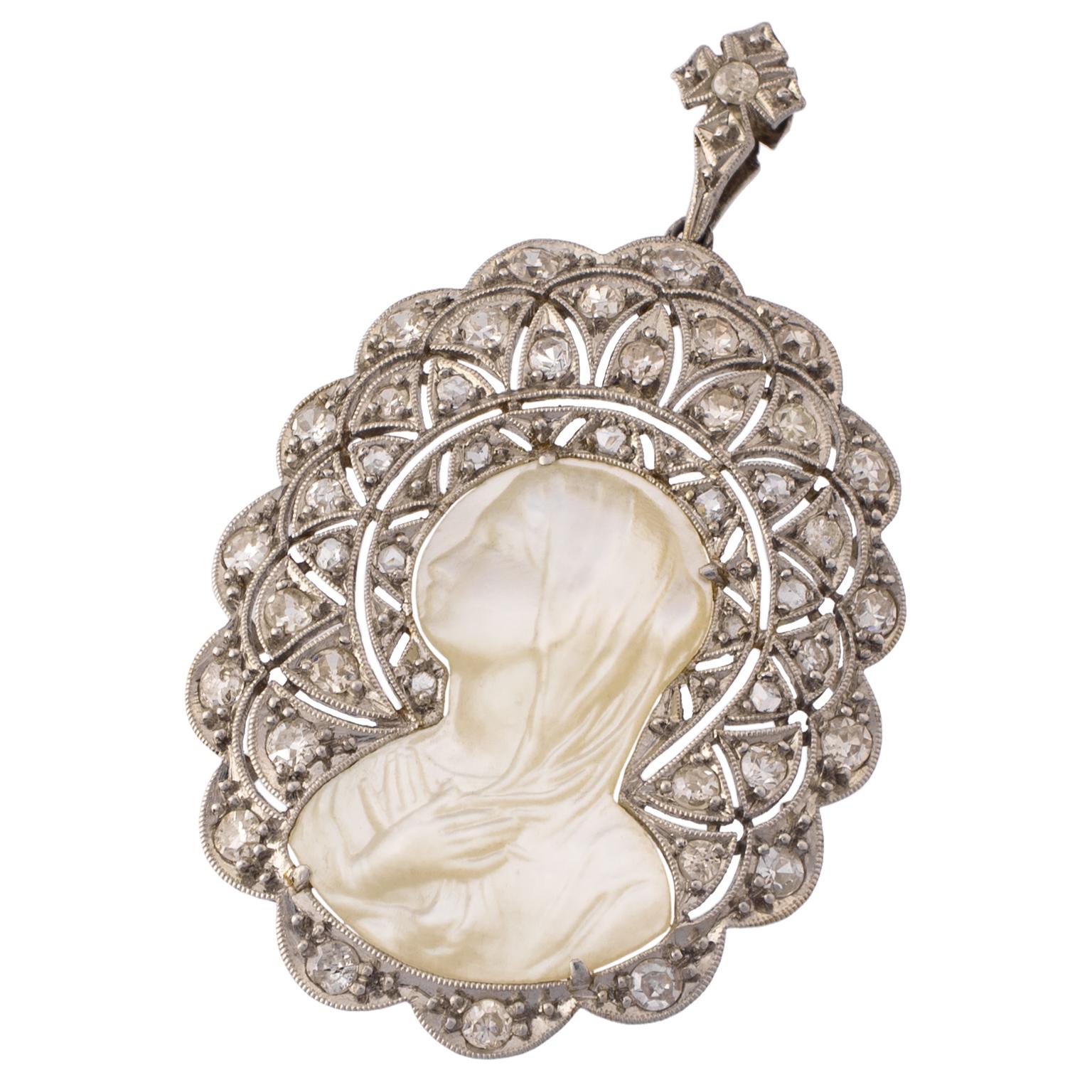 Art Deco Madonna pendant from the first half of the 20th century, in mother of pearl and platinum, set with 43 rose and single cut diamonds, totalling 0.40 carats in weight.
Dimensions: 35 x 27 mm (1.38 x 1.06 in)
