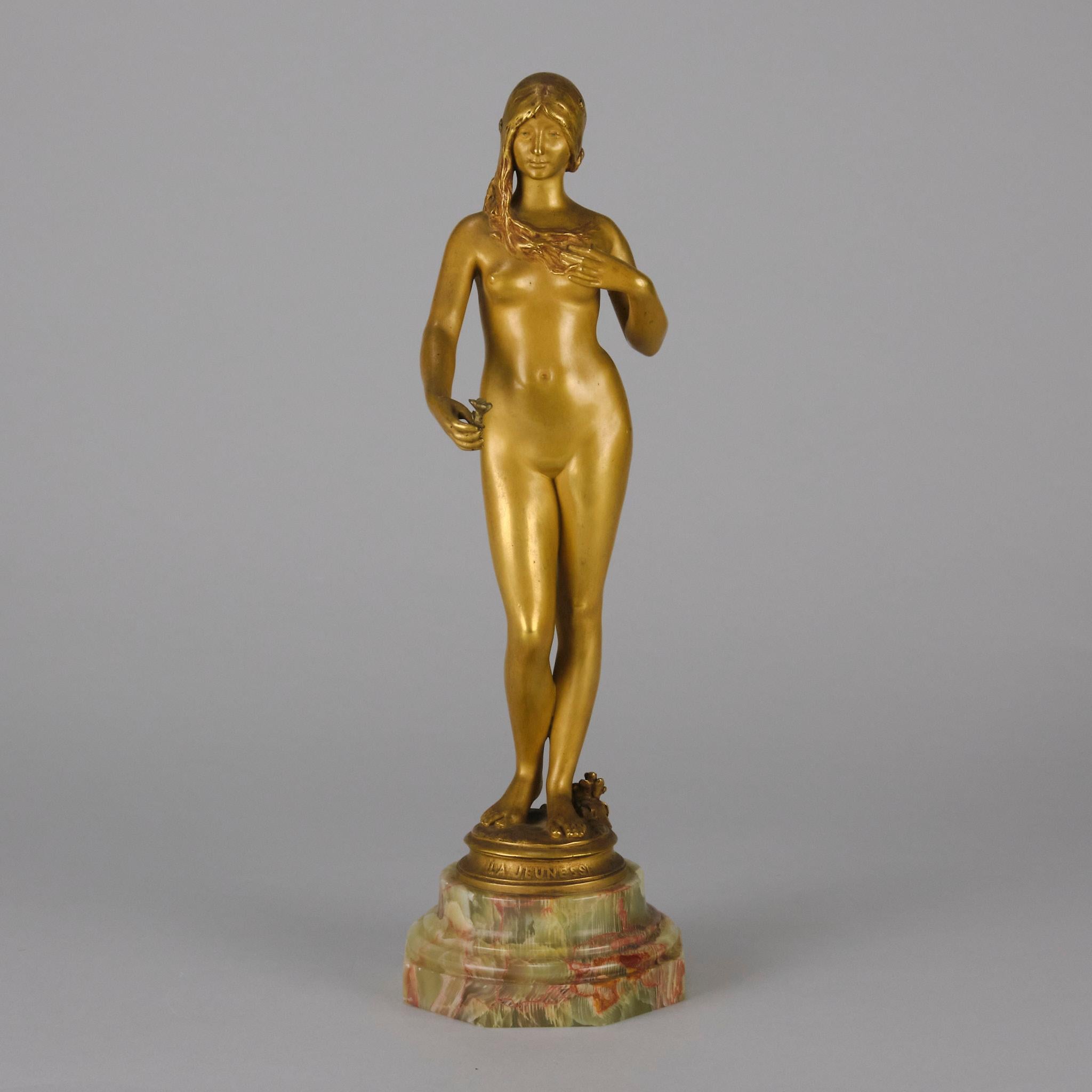 A delightful Art Nouveau early 20th Century gilt bronze figure of a very beautiful young lady holding a flower in her right hand, the surface of the bronze exhibiting fine detail and finish. Raised on a shaped onyx base, titled to the fore, signed