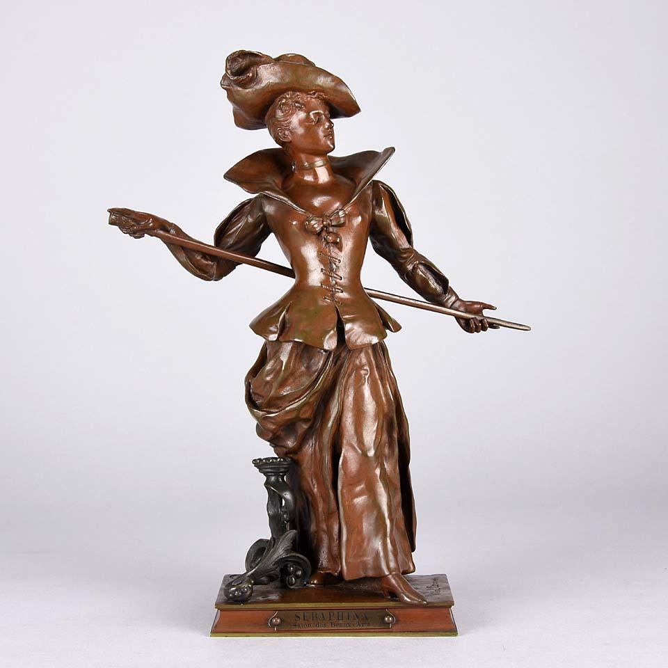 A captivating bronze figure of an attractive beauty in period attire holding a billiard cue behind her back. The surface with excellent hand chased detail and very rich red/brown and golden patina, signed Vital-Carnu and stamped Societe des