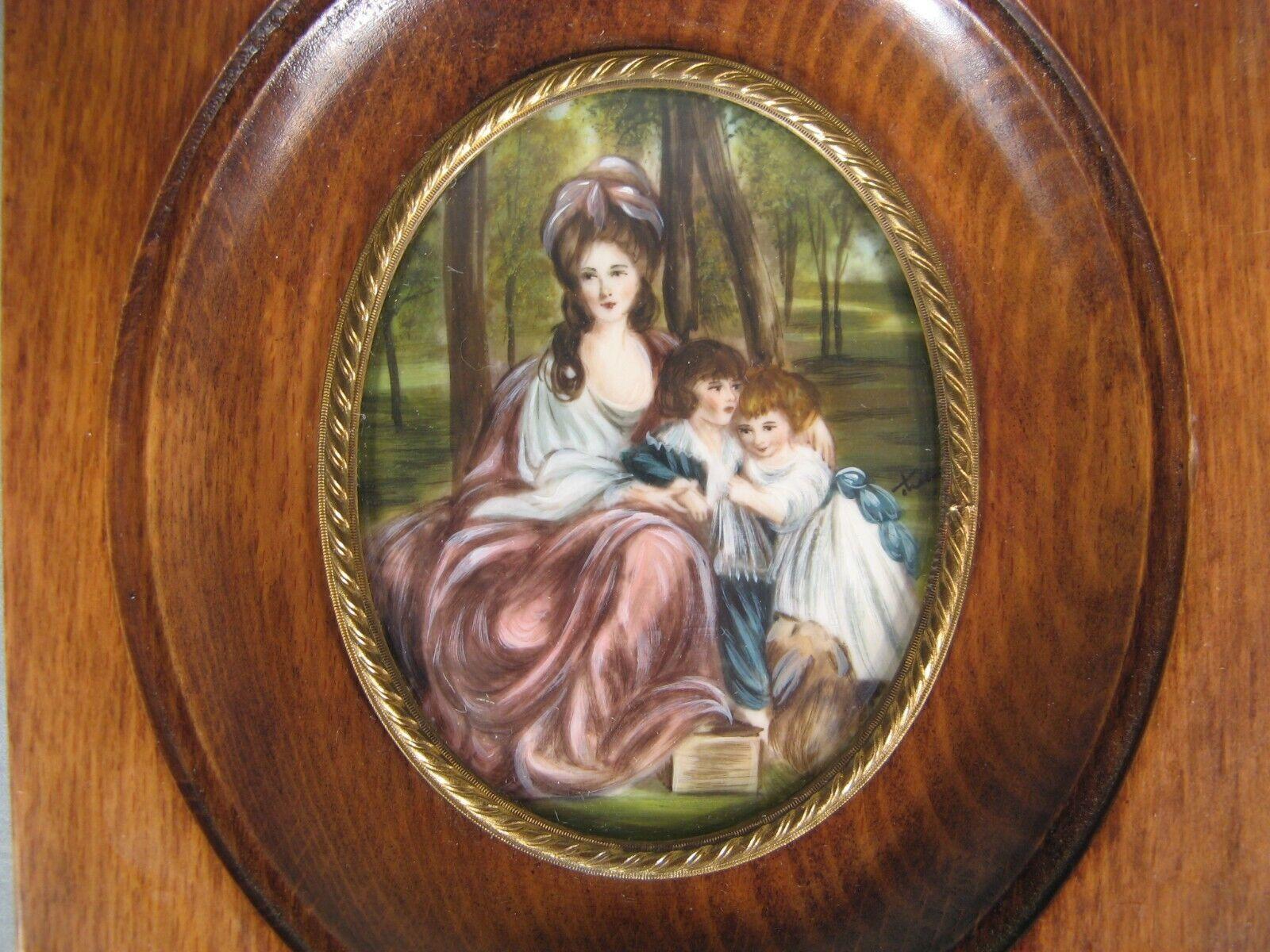 This exquisite hand-painted miniature depicts a young aristocratic woman with her children and their dog. The painting features a faint signature on the middle right side. It is framed under glass in a varnished wood and brass frame, and is designed