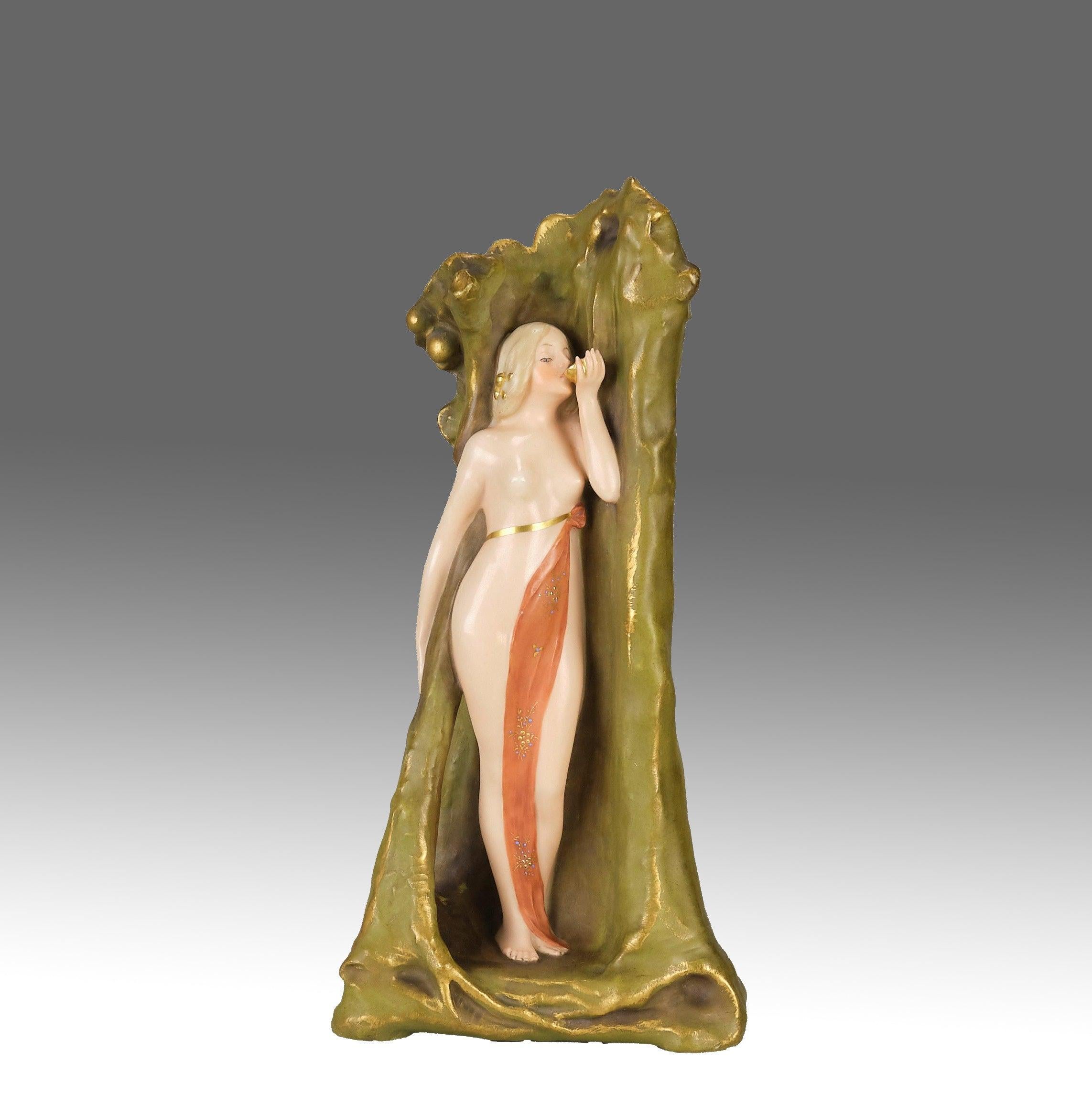 Un bellissimo vaso di terracotta smaltata Art Nouveau, modellato con la figura di una giovane bellezza in piedi che beve da una conchiglia con una toga leggermente drappeggiata sul corpo, con colori e dettagli eccellenti, timbrati e numerati sul