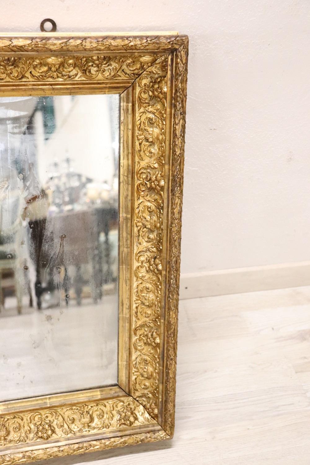 Eleganter antiker italienischer Jugendstil-Wandspiegel aus vergoldetem Pappelholz aus dem frühen 20. Jahrhundert. Der Rahmen zeichnet sich durch eine aufwendige florale Dekoration mit Blumen und Elementen des klassischen Geschmacks aus. Der Spiegel