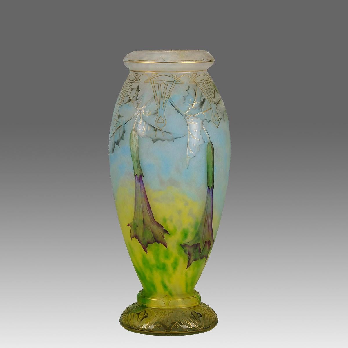 Magnifique vase en verre camée Art Nouveau du début du 20e siècle, gravé et émaillé de Datura en fleurs dans un paysage vibrant. Le dessin est rehaussé d'un motif doré sur la surface pour donner une profondeur de champ spectaculaire, présentant