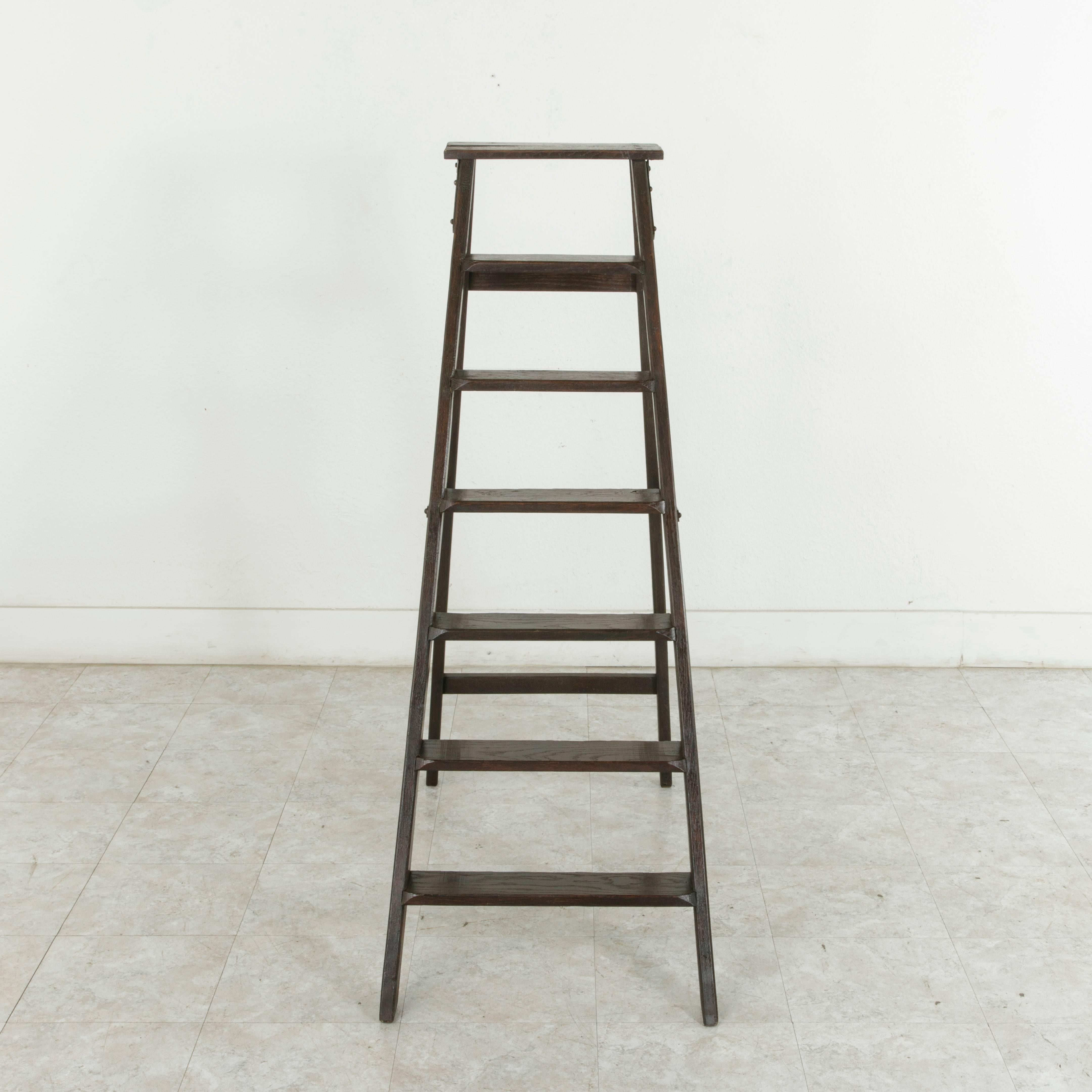 Originally used in a French library, this folding ladder, constructed of oak with mortise and tenon joinery, would be a handsome addition to any space with hard to reach shelving. It features iron hinges that allow it to be folded, and, while still