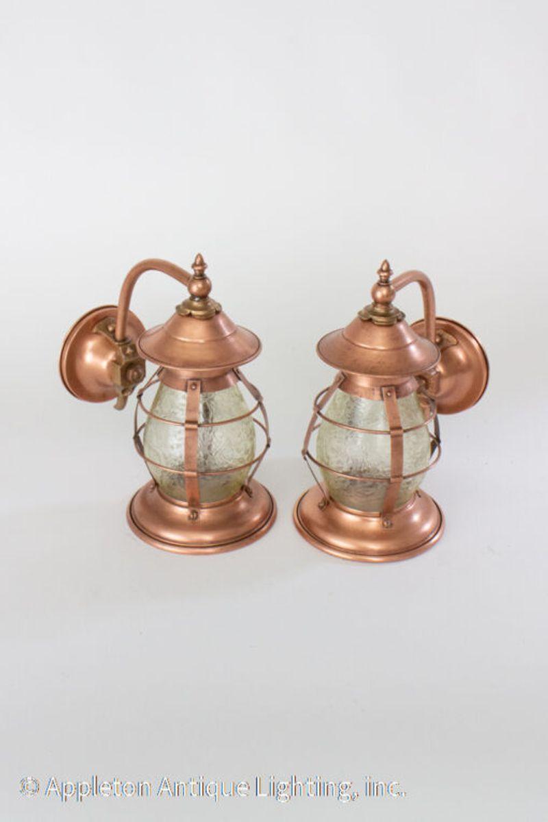 Early 20th century Arts & Crafts copper sconces with original gluechip textured amber glass. These sconces are in a lantern shape similar to vintage nautical lanterns with a cage shape.

Dimensions: 6.5 × 9 × 12 in.