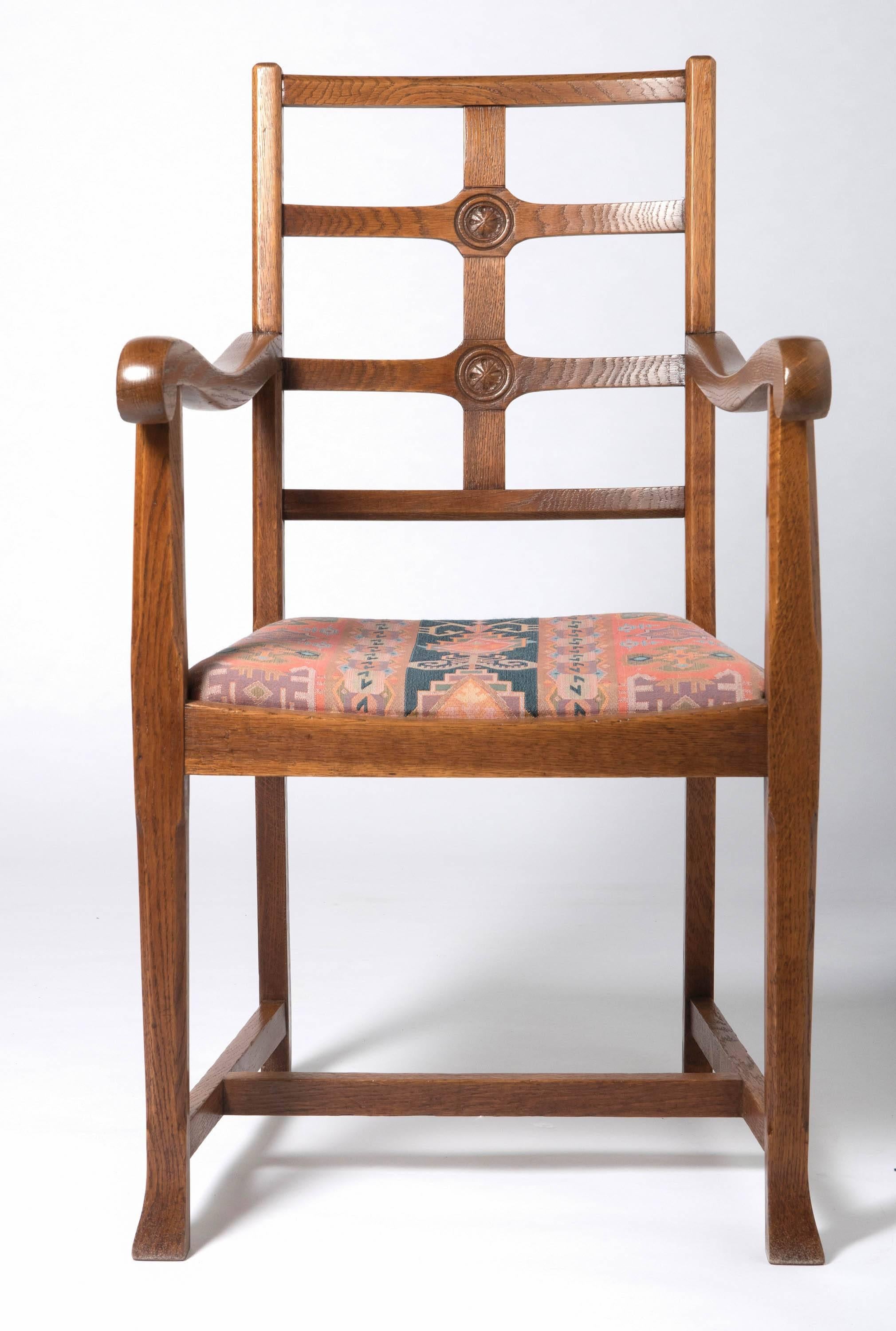 An early 20th century Arts & Crafts oak framed elbow chair, in the manner of Heals.
The lattice back with 2 carved rosettes. The drop in seat raised on chamfered block legs.
Measures: H 97 cm, W 54 cm, 43 cm, seat 46 cm
England, circa 1920.