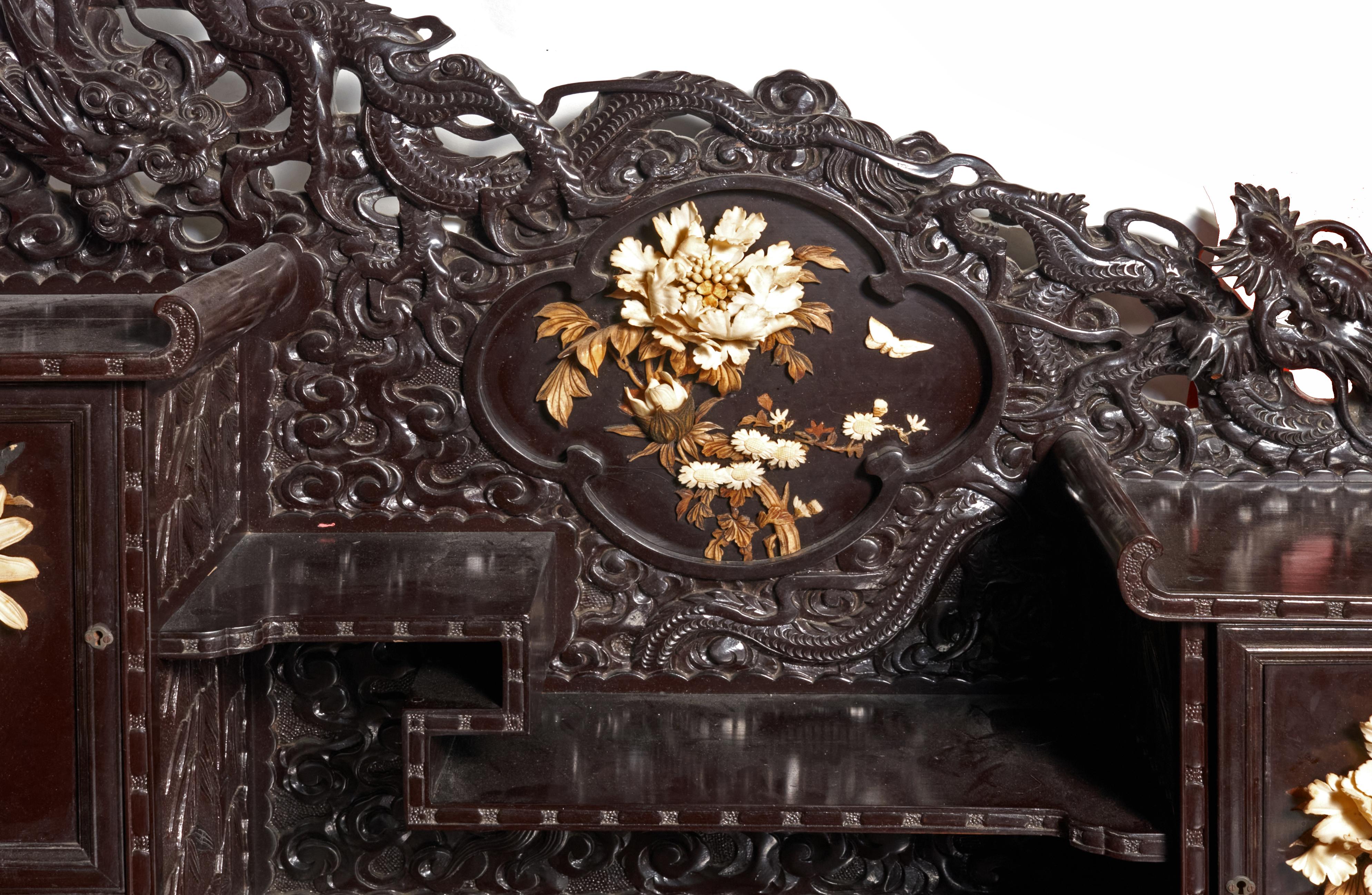 Exceptional early 20th century Chinese export desk and matching chair in finely carved rosewood and possibly mahogany. The desk has beautiful dragon detail carved across the asymmetrical top and 3 dimensional bone flower detail on the back panel and