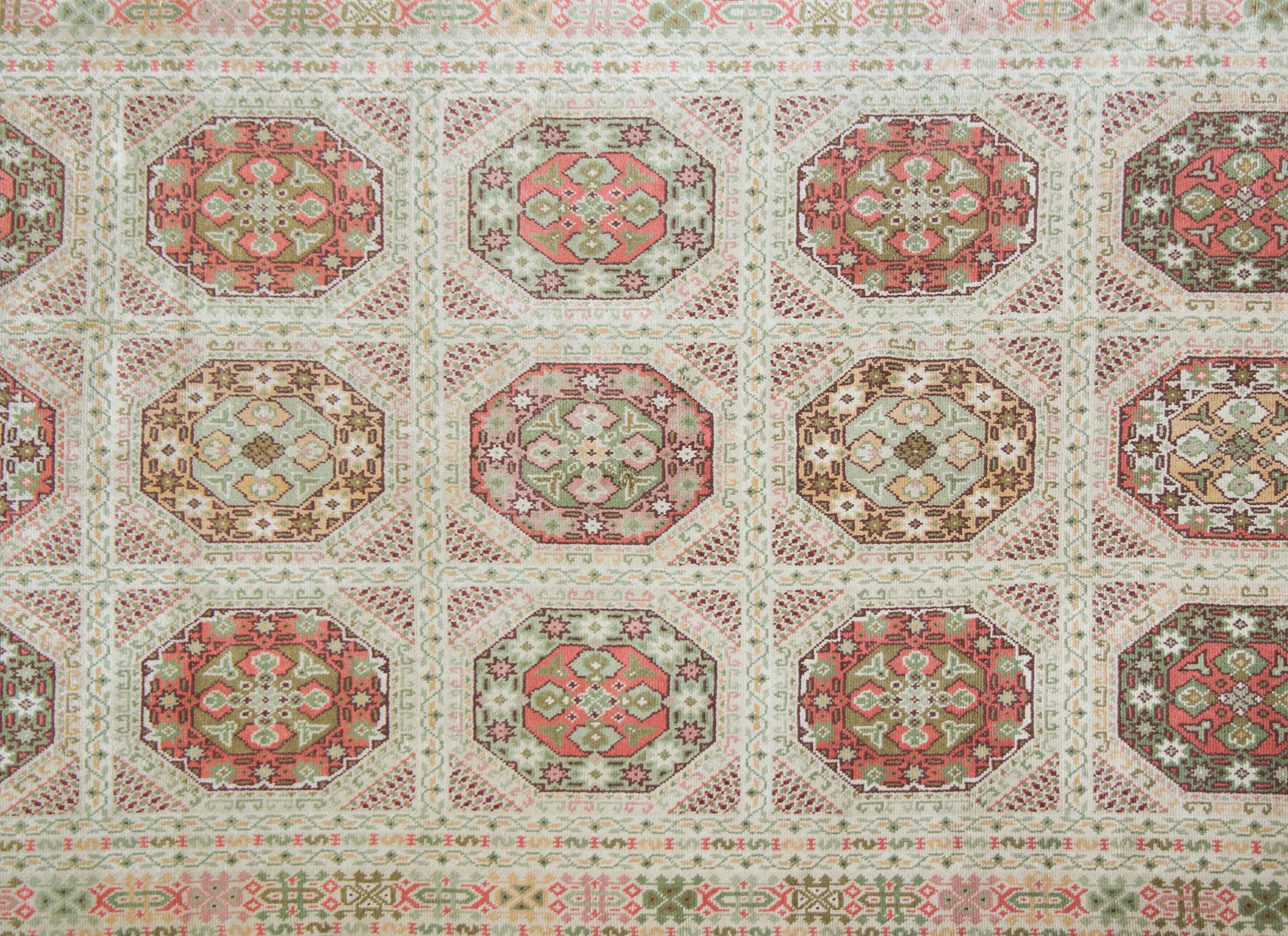 A wonderful early 20th century Austrian hand knotted wool rug with a repeated octagonal medallion and trellis pattern with myriad stylized flowers and scrolling vines and surrounded by a border with multiple thin stripes with more stylized flowers