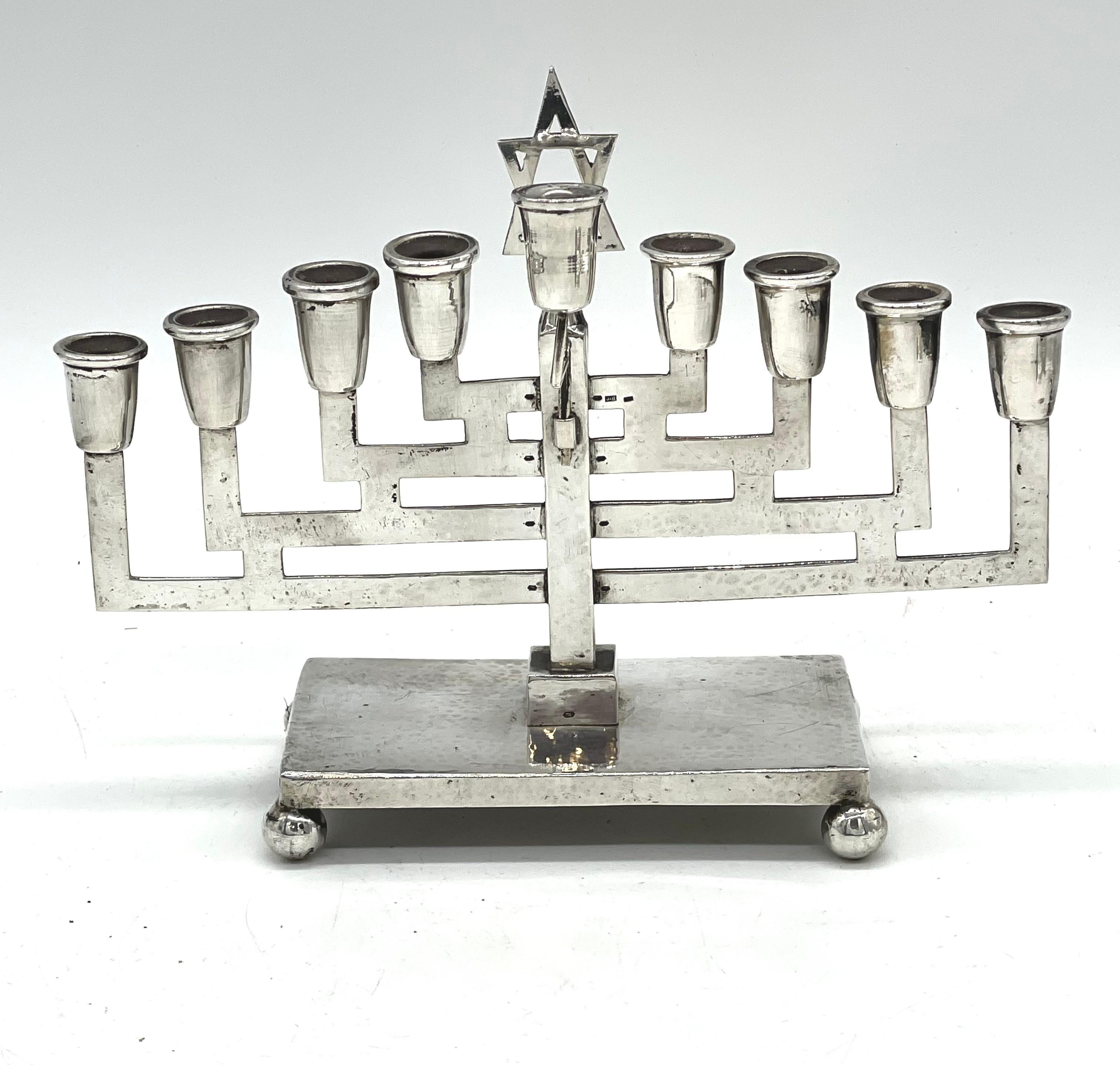 Austrian silver Hanukkah lamp is handmade and features nine candleholders in Art Deco style. The stylized candleholders are supported by tiers of geometric patterns with a harmonious toppling of arranged, broken up lines accompanied by detailed