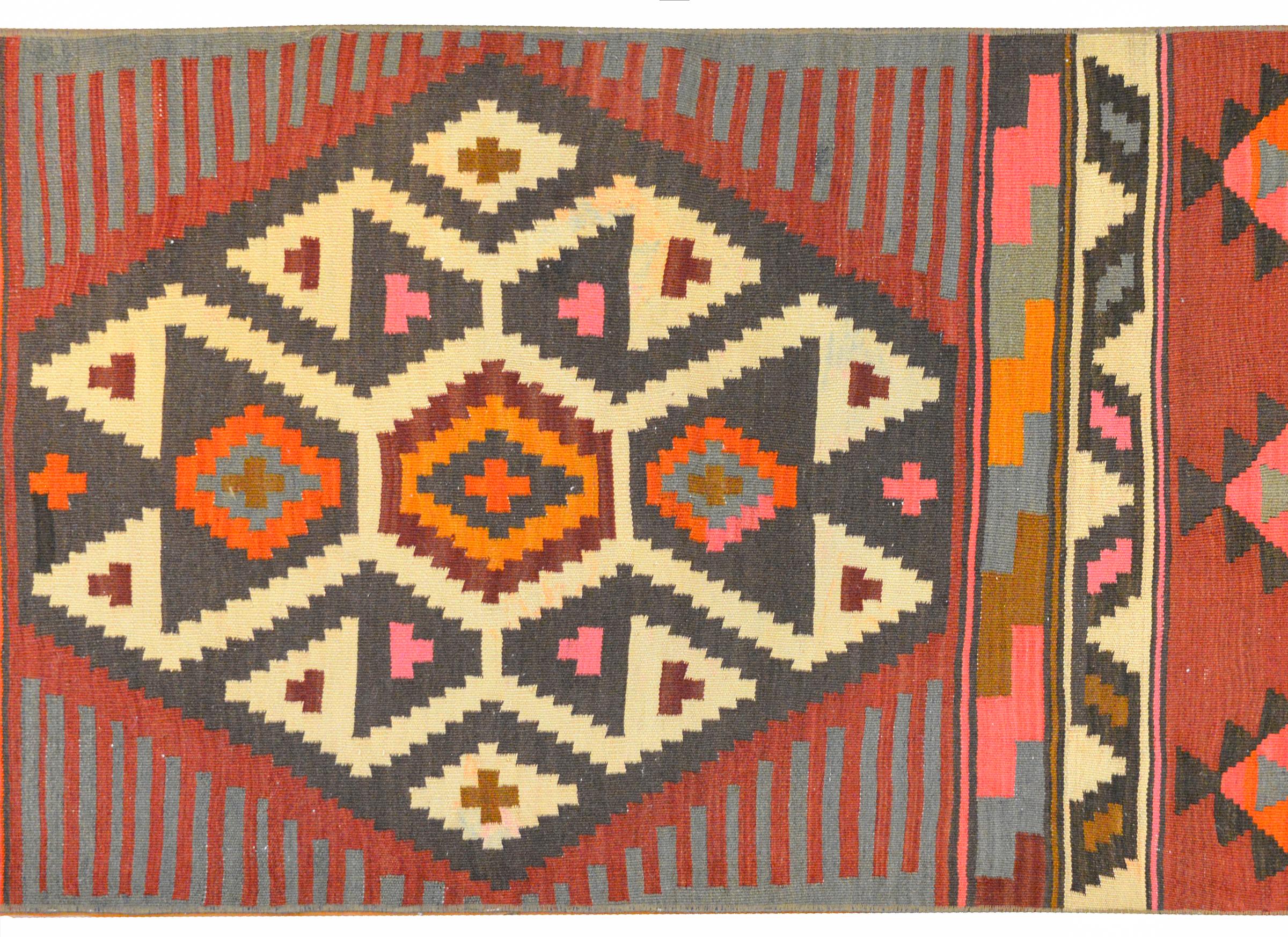 An early 20th century Azerbaijani Kilim runner with with a bold geometric pattern woven in crimson, orange, gold, gray, pink, white and black vegetable dyed wool.