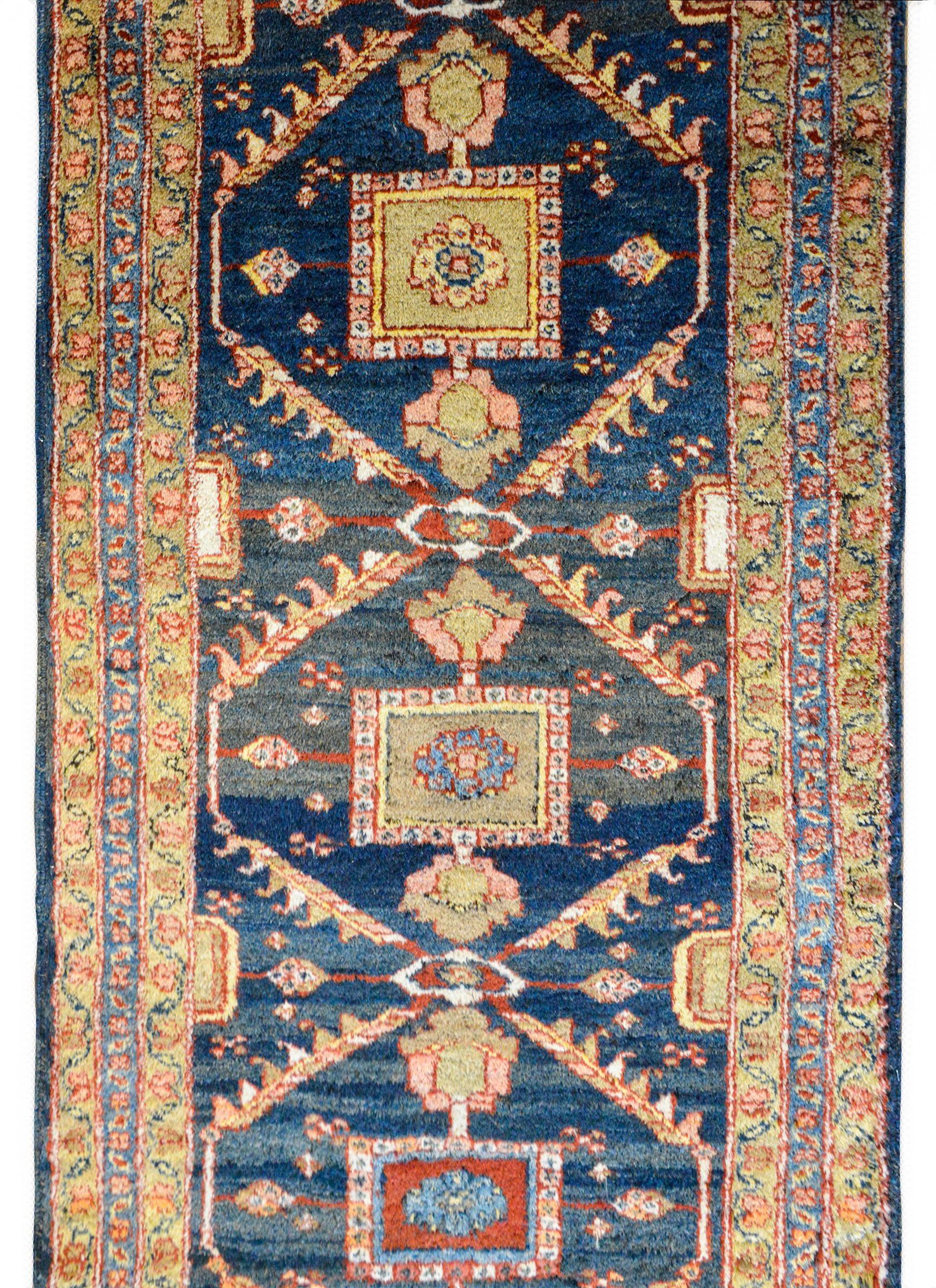 A beautiful 20th century Persian Azari runner with seven large medallions with stylized flowers and leaves woven in crimson, pink, white, brown, and pale green, all against an Abrash indigo background. The border is complex, composed of a petite