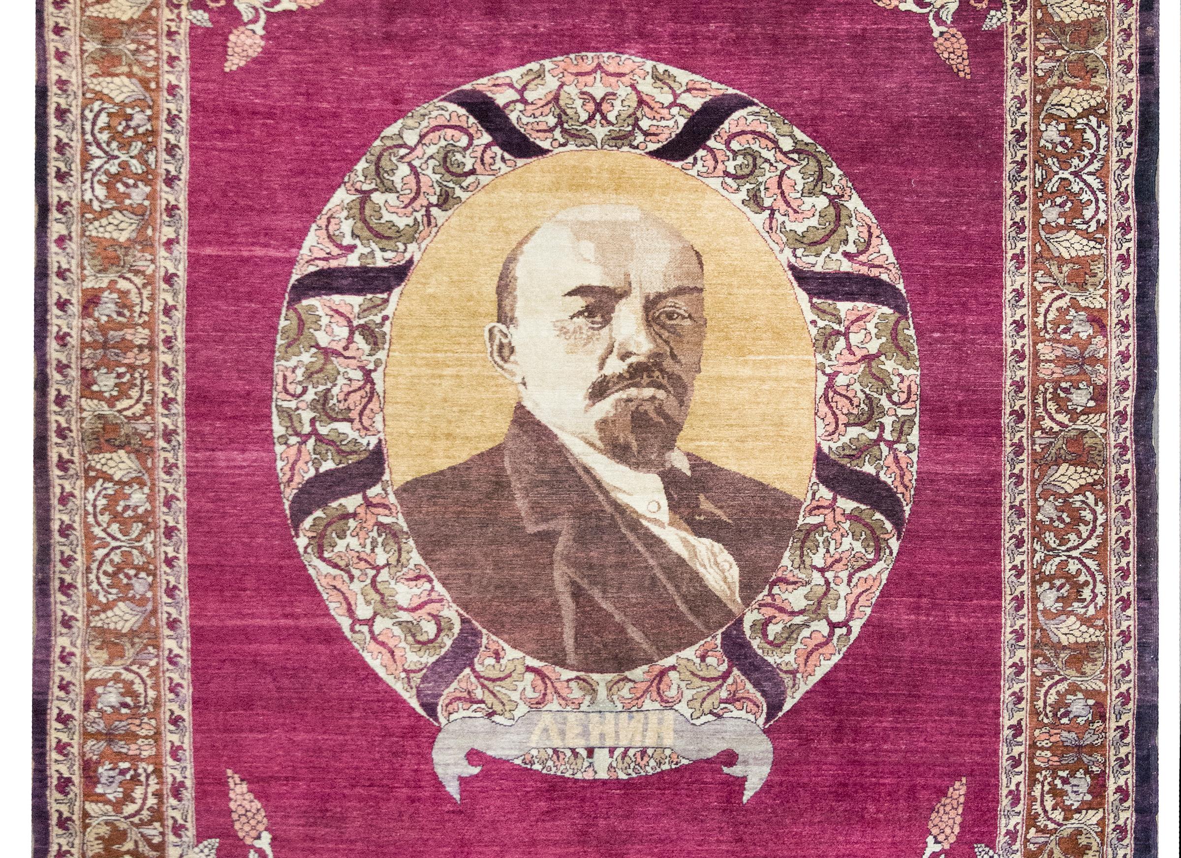 A rare and commanding piece of textile history, this early 20th-century Azerbaijani pictorial Karabakh rug is a masterwork of both symbolism and craftsmanship. At its heart, a striking portrait of Vladimir Lenin is encircled by a lush floral wreath,
