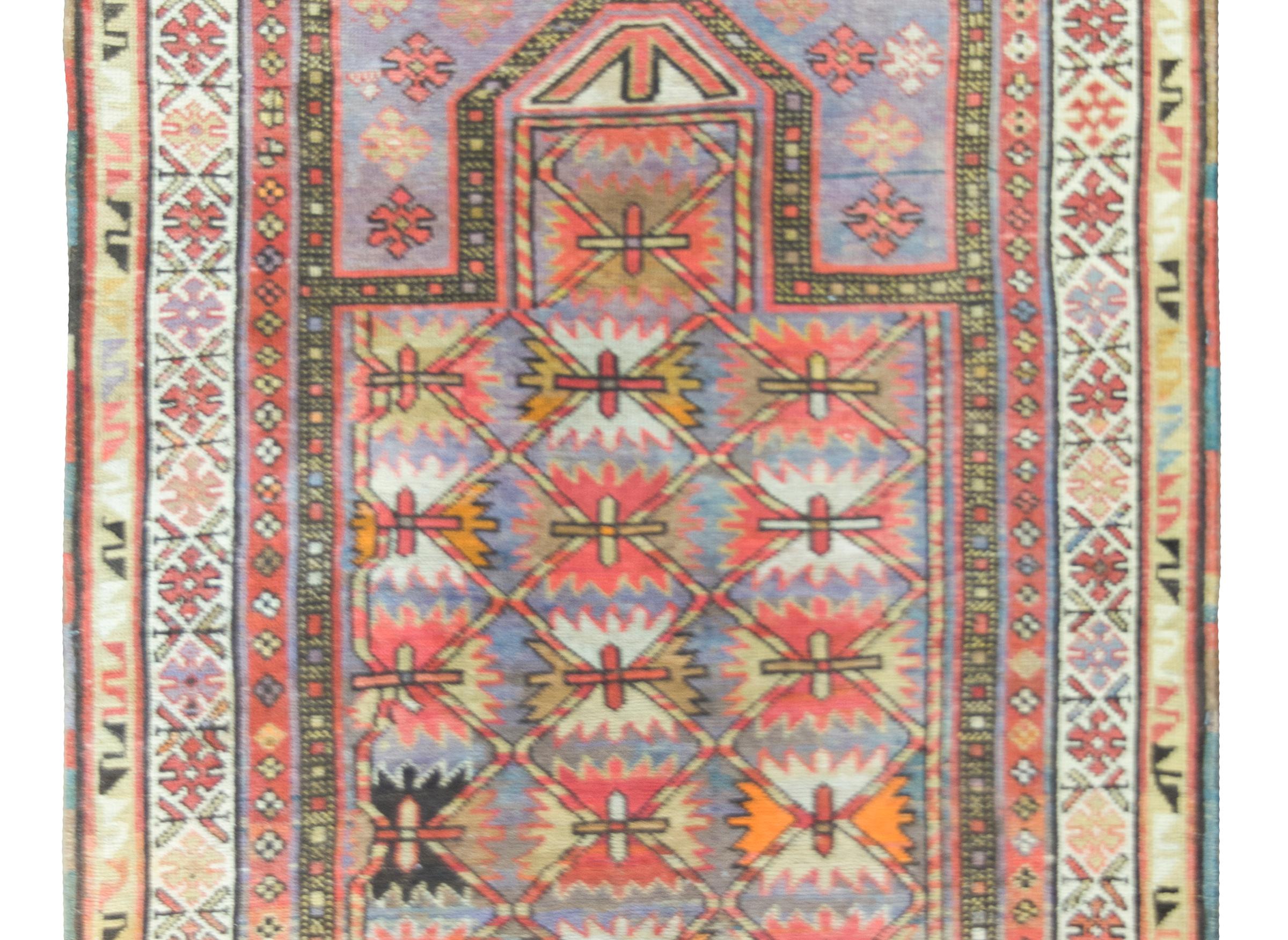 A beautiful early 20th century Persian Kuba prayer rug with a central field covered in stylized flowers and surrounded by a complex border with even more stylized flowers, and all wocenin coral, orange, violet, cream, and gold.