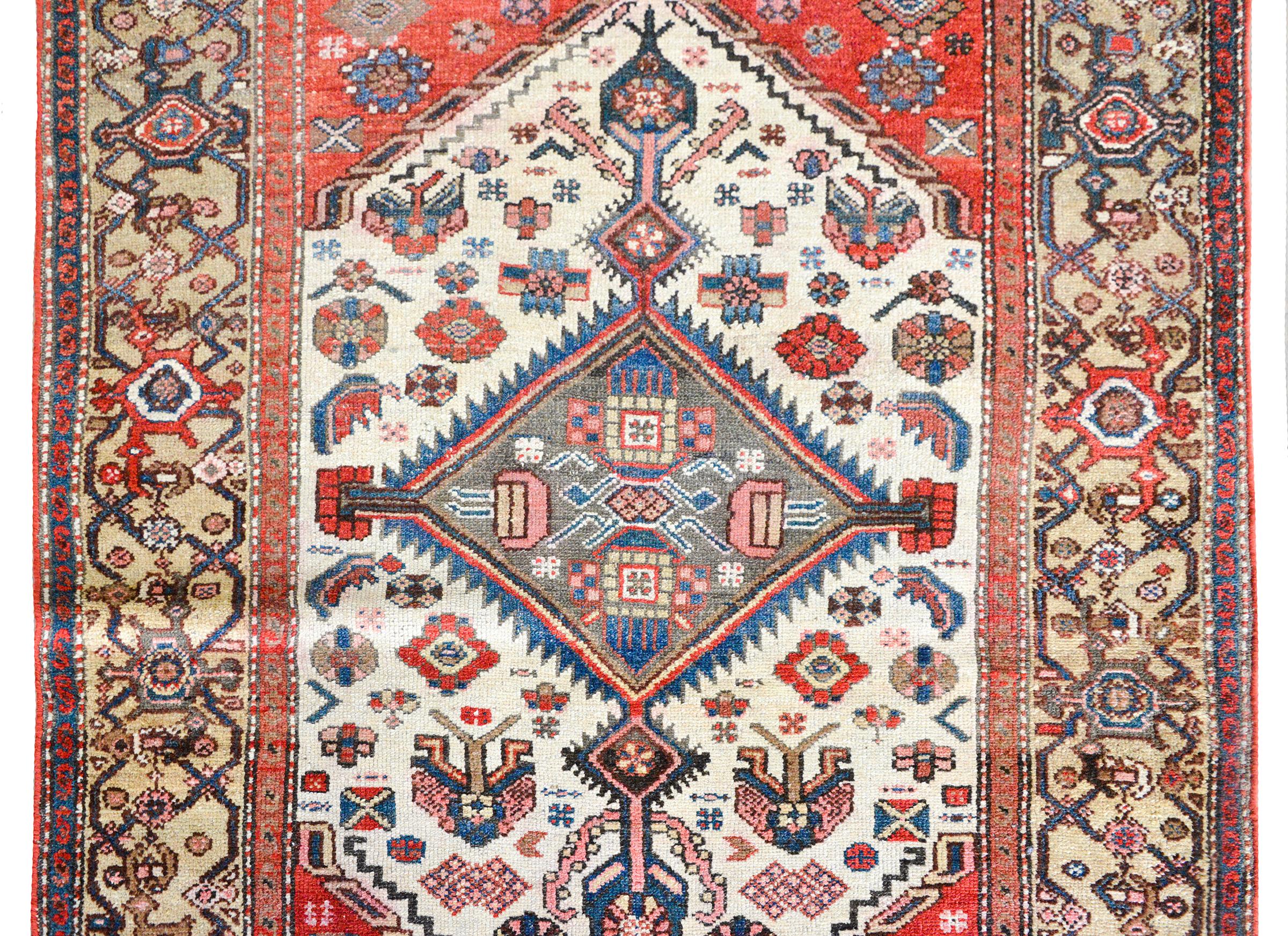 A wonderful early 20th century Persian Bakhtiari rug with a fantastic tribal pattern containing myriad stylized flowers, all woven in crimson, light and dark indigo, pink, and white, and surrounded by a wide stylized floral and scrolling vine