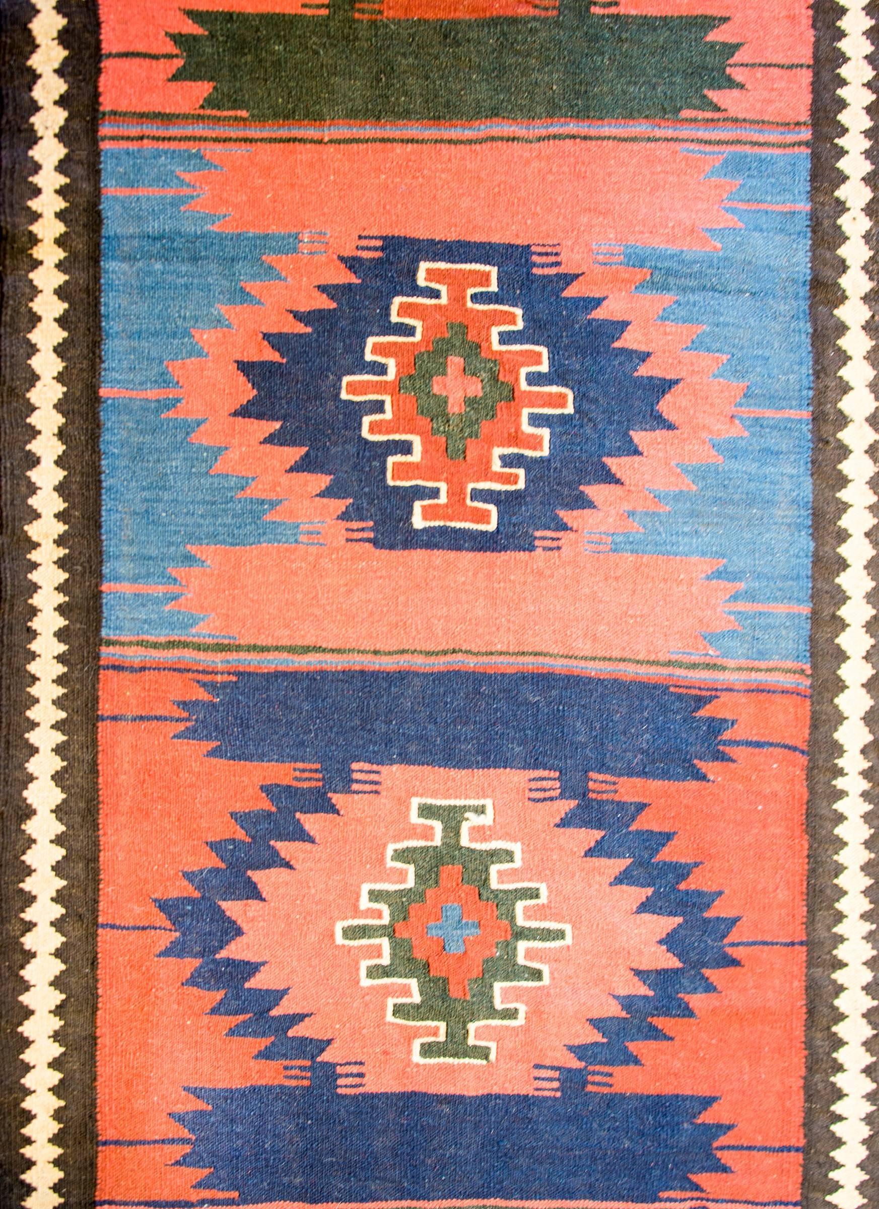 An early 20th century antique Persian Bakhtiari runner with ten diamond medallions woven in crimson, salmon, indigo, and green surrounded by a simple harlequin striped border.