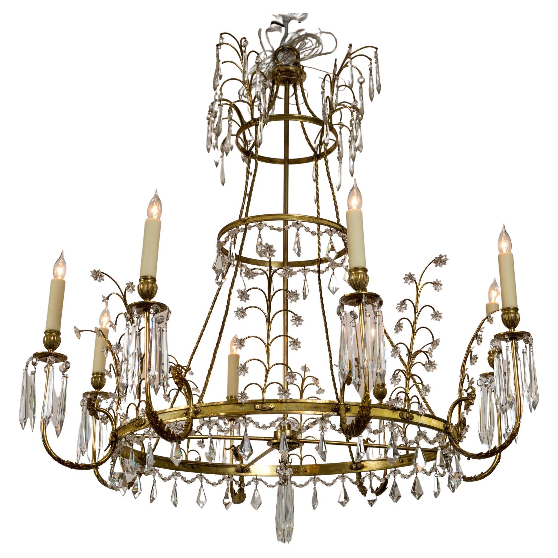 A light and airy Baltic 8-arm brass and bronze chandelier composed of three circular tiers; the top tier offering a dramatic waterfall effect of crystals falling from four brass branches while its lowest and largest circular tier greets you with 8