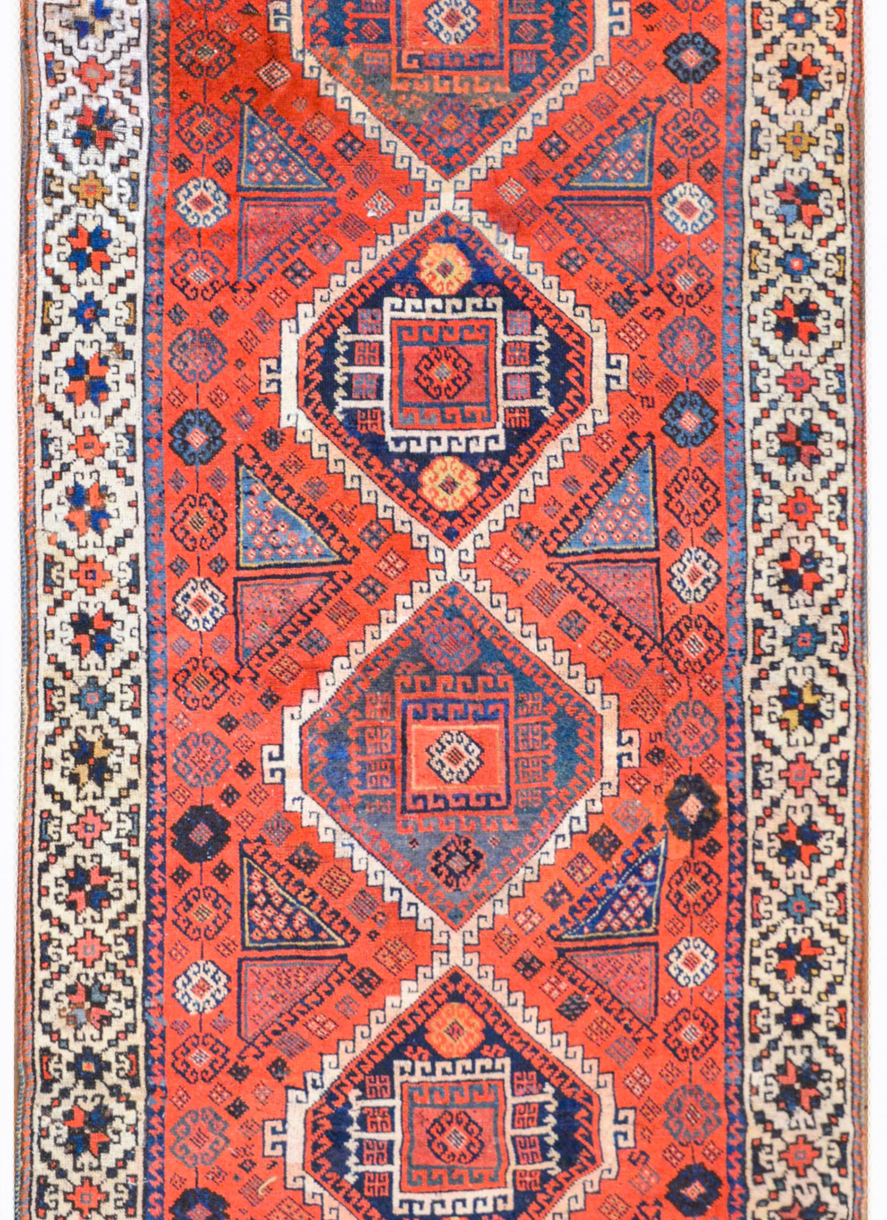 A wonderful early 20th century Eastern Anatolian Kurdish rug with four diamond medallions each with a stylized floral and vine pattern woven in crimson, indigo, white, and cream-colored wool amidst a field of densely woven stylized flowers against a