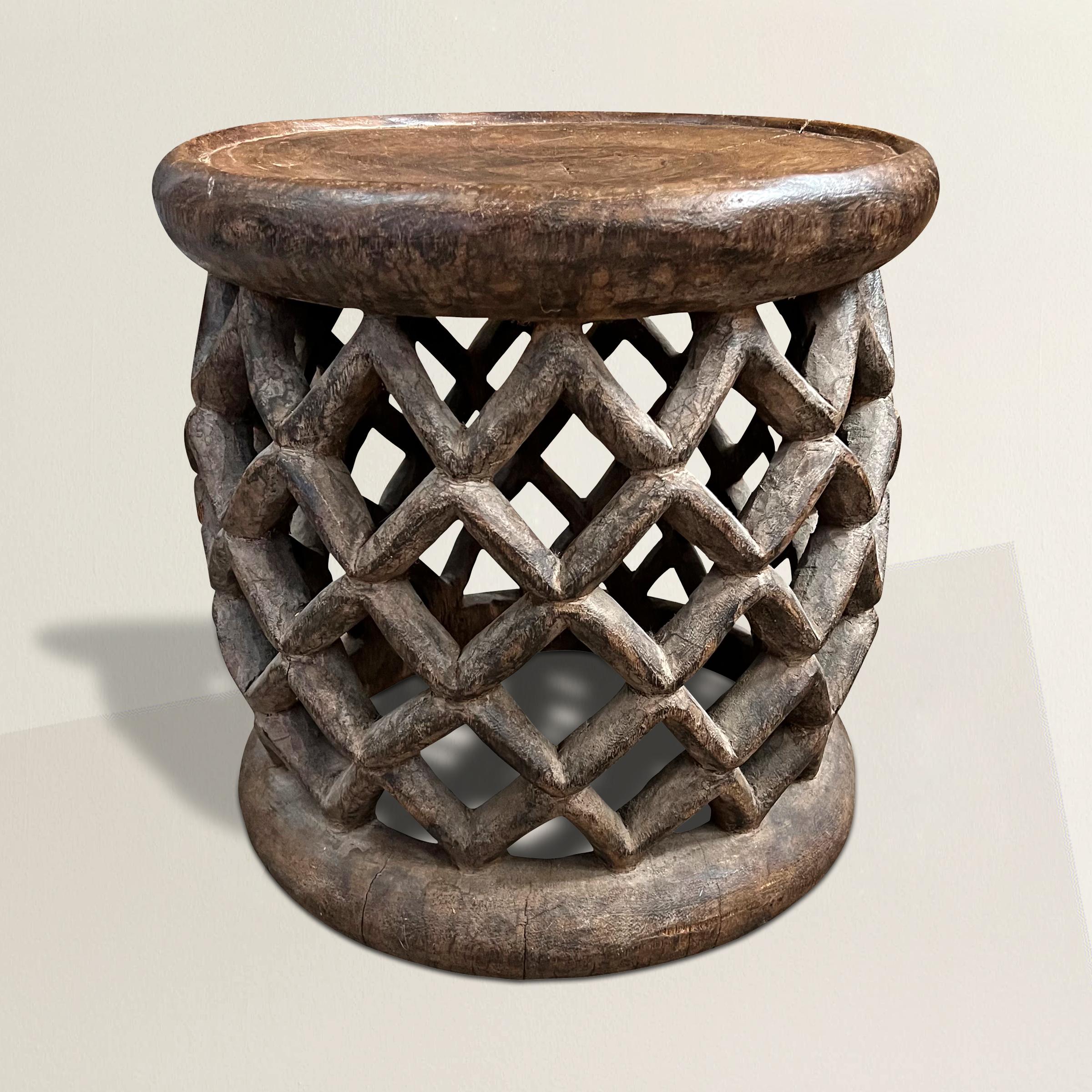 A stunning and expressive early 20th century Bamum stool carved from one piece of wood with an incredible stylized frog motif supporting a solid top with a large lip.