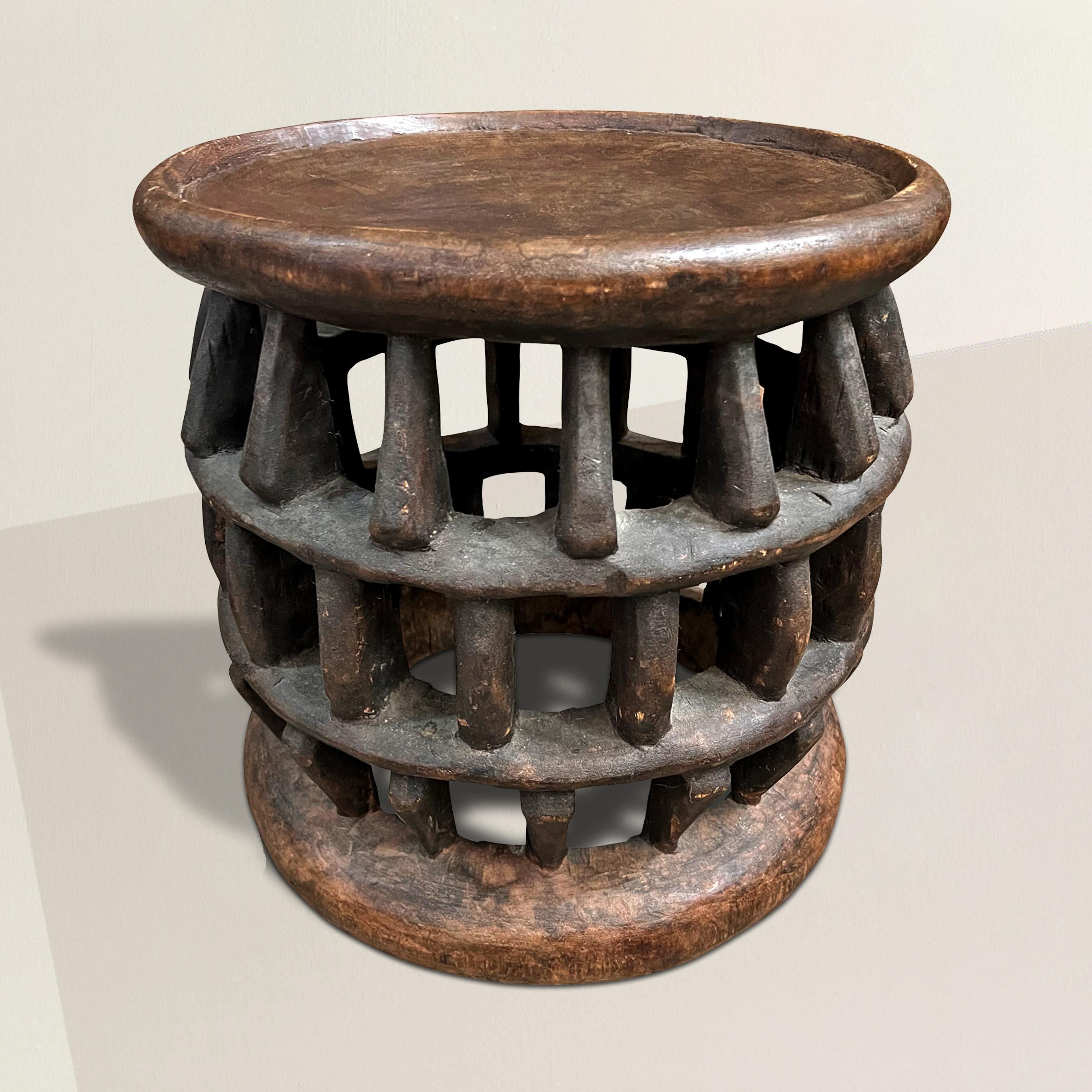 A modern-in-spirit early 20th century Bamum stool carved from one piece of wood with an incredible lattice work pattern supporting a solid top with a large lip. The perfect side table next to your favorite armchair, next to your bed, or tucked under