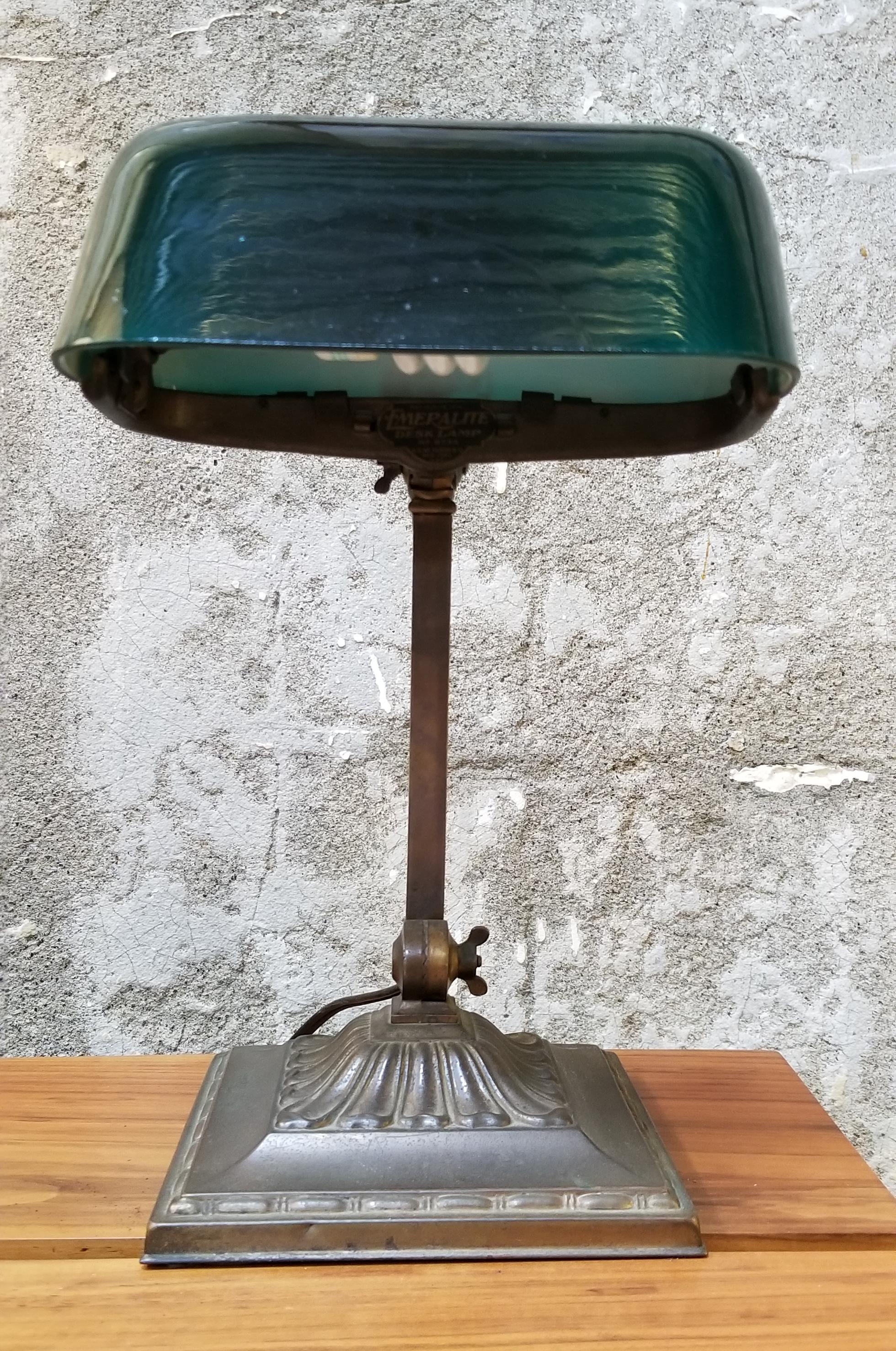 Period bankers / students / library table lamp by Emeralite Lamp Company. Circa. 1920. Beautiful emerald green cased glass shade. Two adjustable lighting positions. Original patina to base. Retains Emeralite label.

EMERALITE
Bellova and