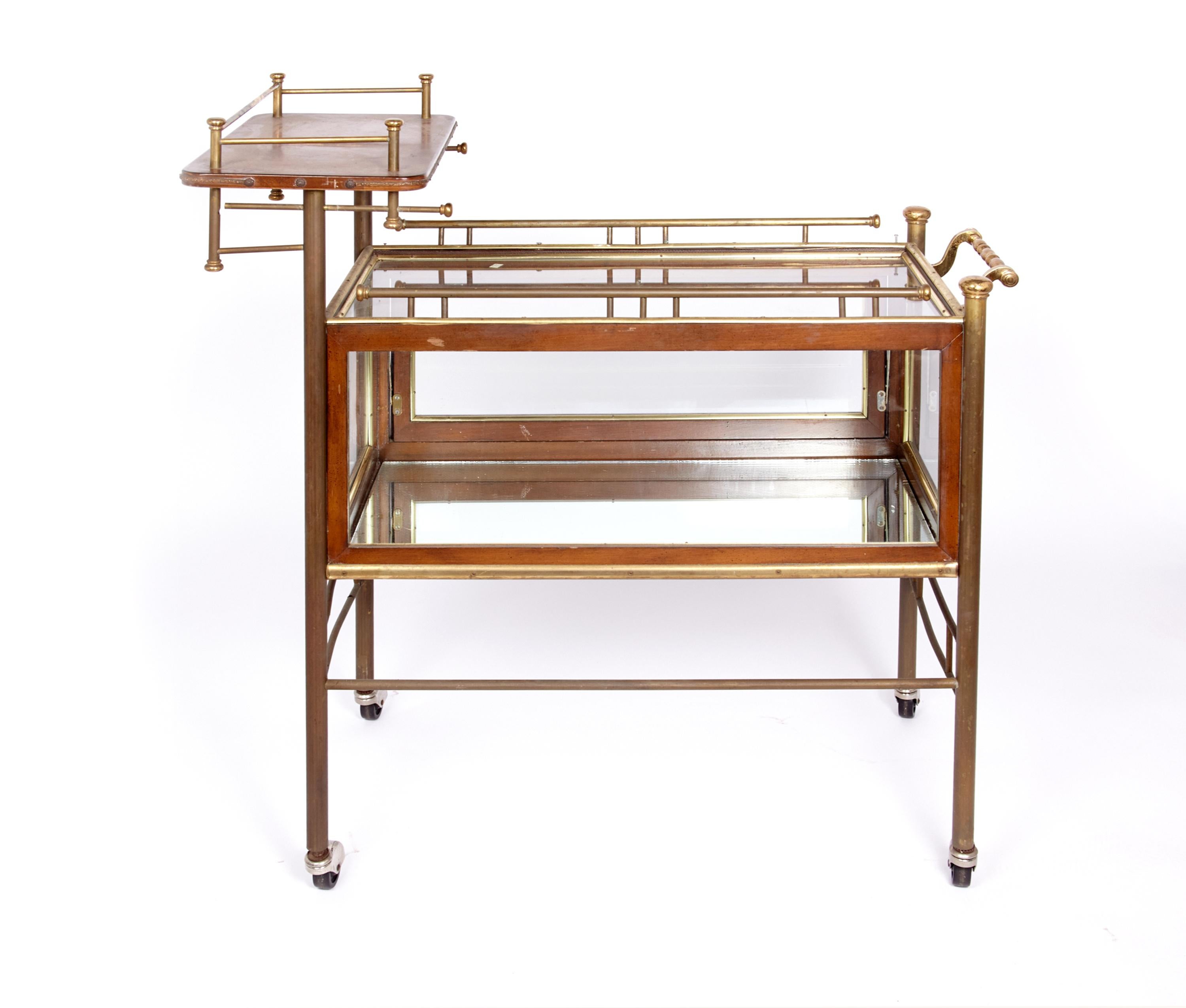 Fabulous rare bar or tea cart with enclosed glass case to display your delicacies whether they be sweet or savory. Beautiful wood and brass with 4 casters to make serving your guests a pleasure. Glass case has flip down front for easy access. The