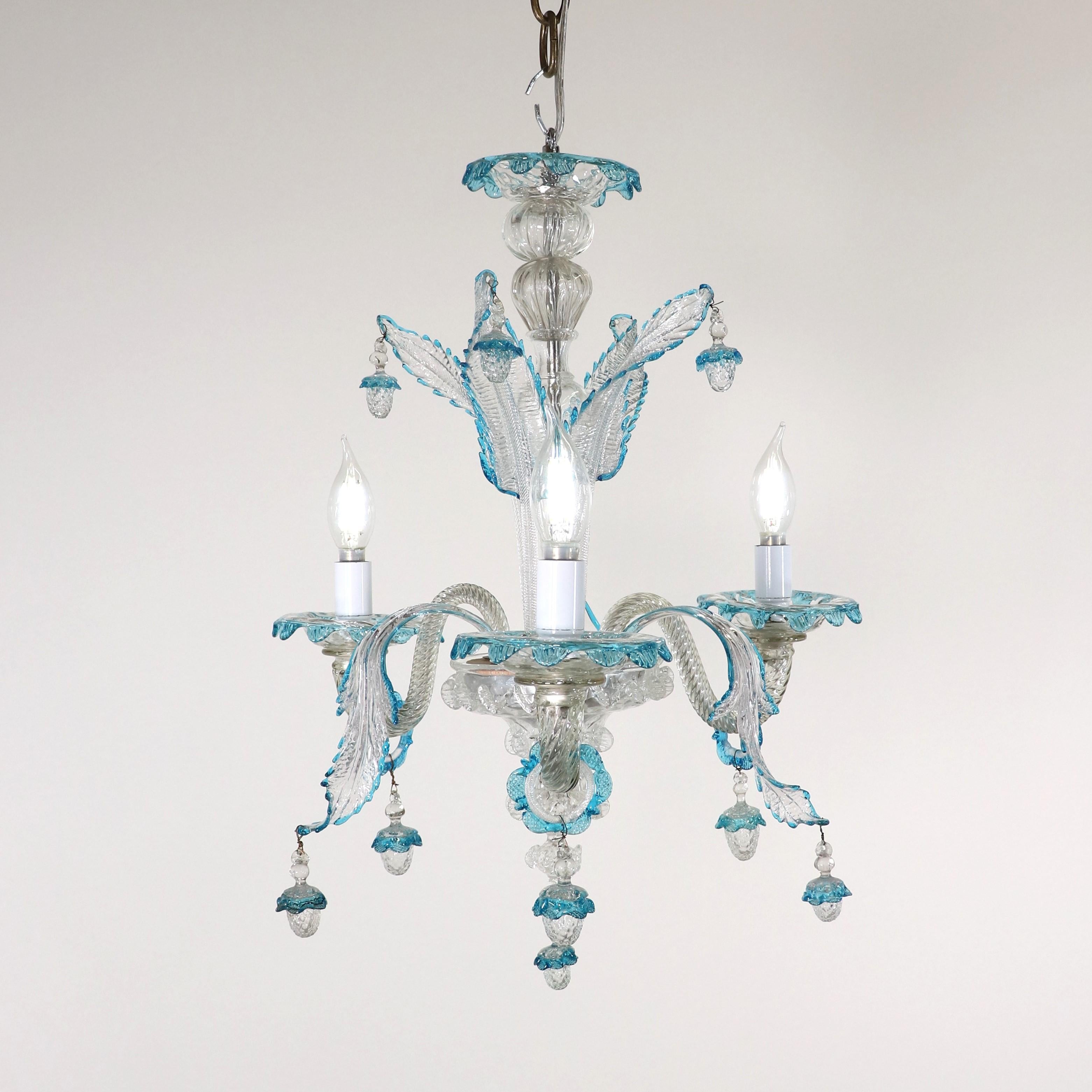 This handcrafted cristallo Murano chandelier has three scroll arms and features a bulbous center column with sprouting natural details, stylized here with leaves and acorn-shaped ornaments. The body and arms of this piece are made of clear,