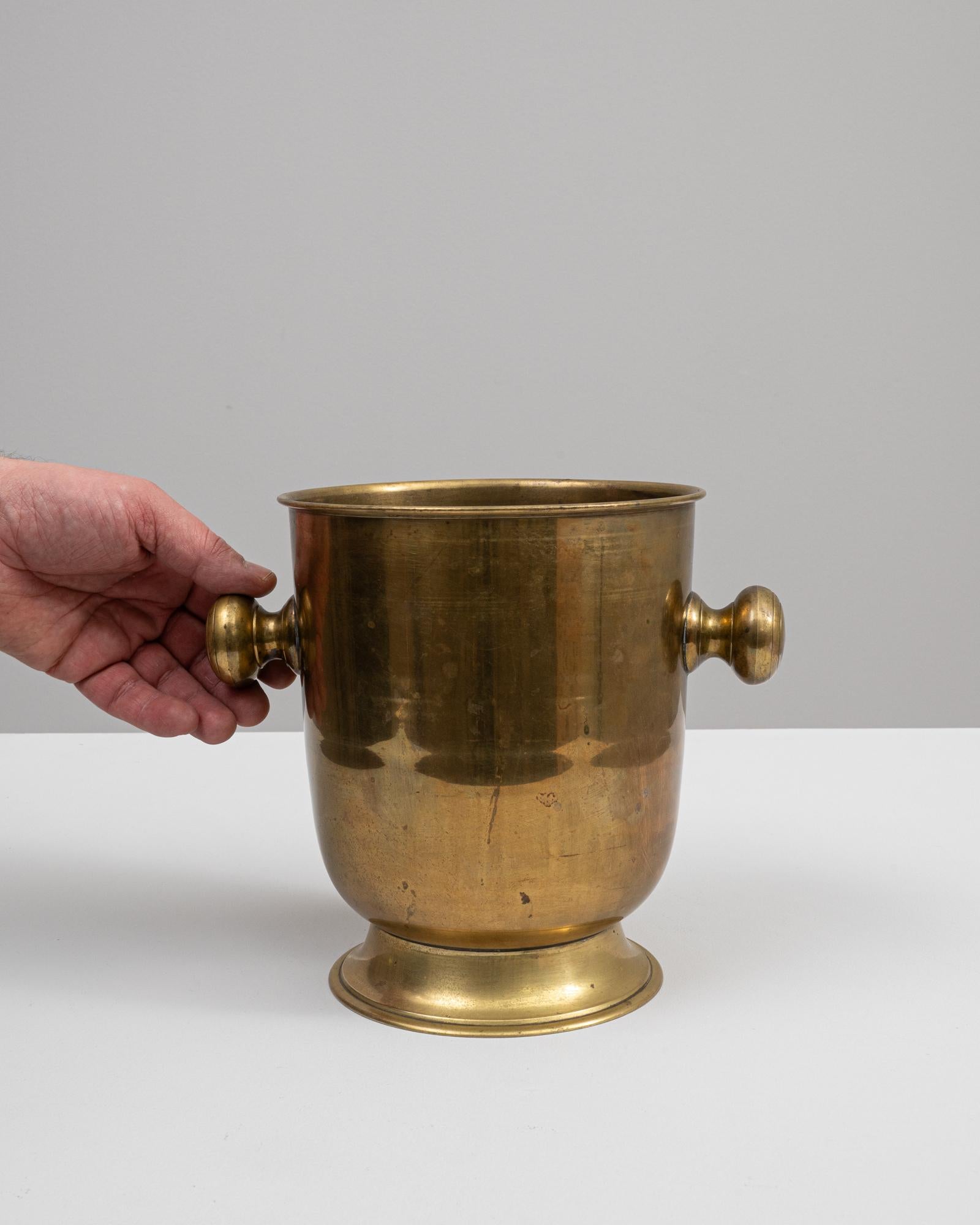 Behold the resplendent Early 20th Century Belgian Brass Ice Bucket, a piece that marries functionality with an air of sophisticated history. Crafted in the heart of Belgium, this brass bucket radiates a warm, golden glow, its patina telling tales of