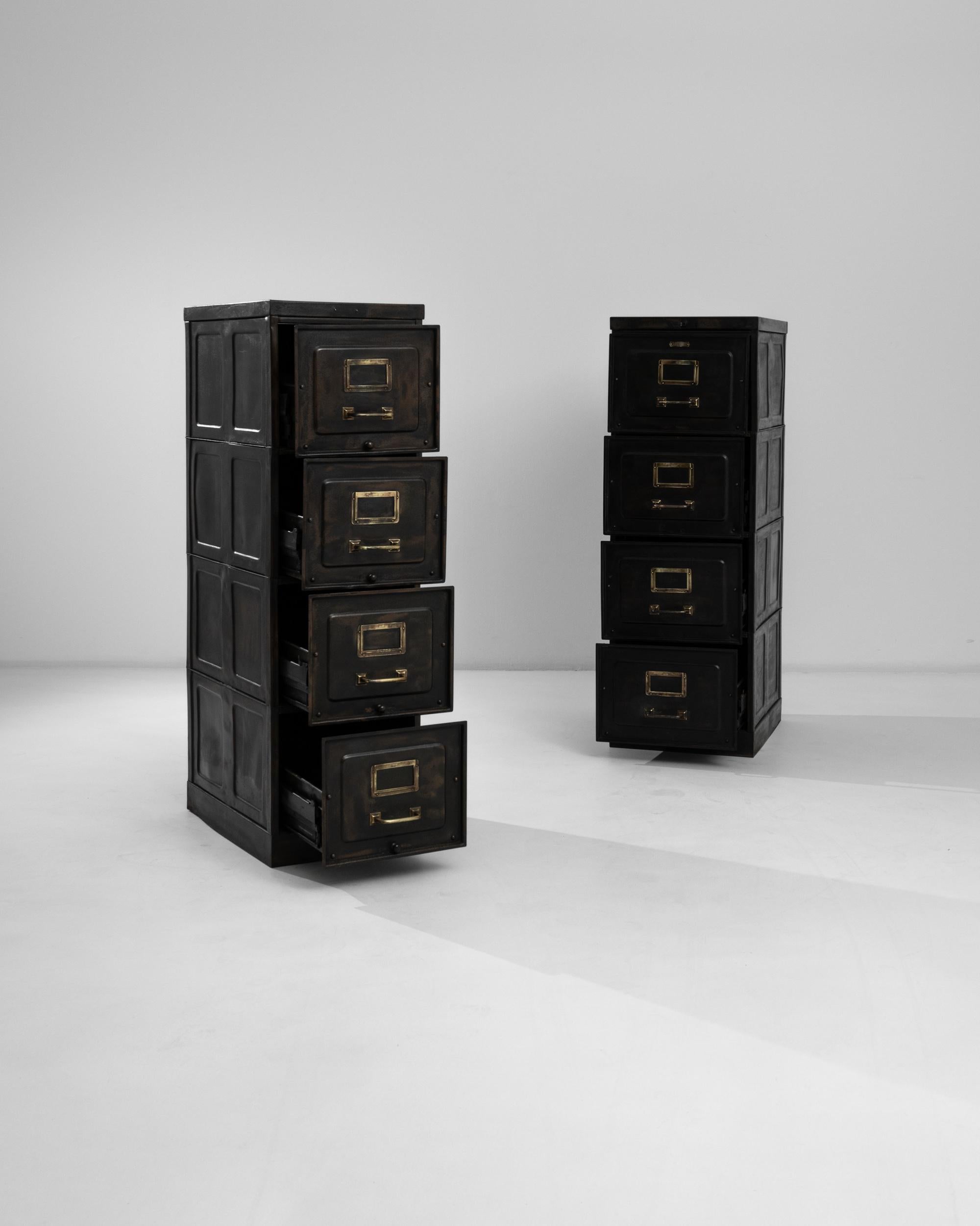 This pair of industrial metal cabinets were manufactured circa 1900 in Belgium by H.E. Longini, attested by the brass manufacturer's plate. Four spacious drawers are equipped with brass pulls and label holders that glimmer against the darkness of
