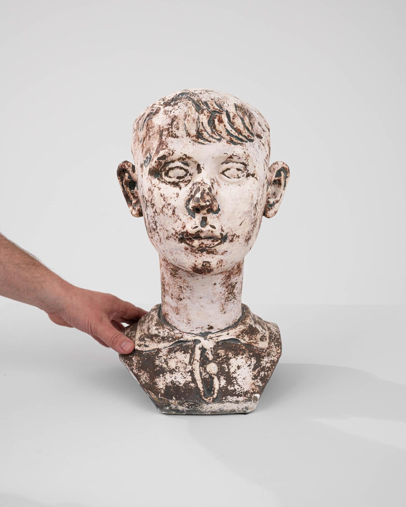 Experience the timeless charm of our Early 20th Century Belgian Plaster Bust, a captivating depiction of youthful innocence and elegance. Crafted with meticulous detail, this exquisite piece showcases the enduring beauty of a young boy adorned in a