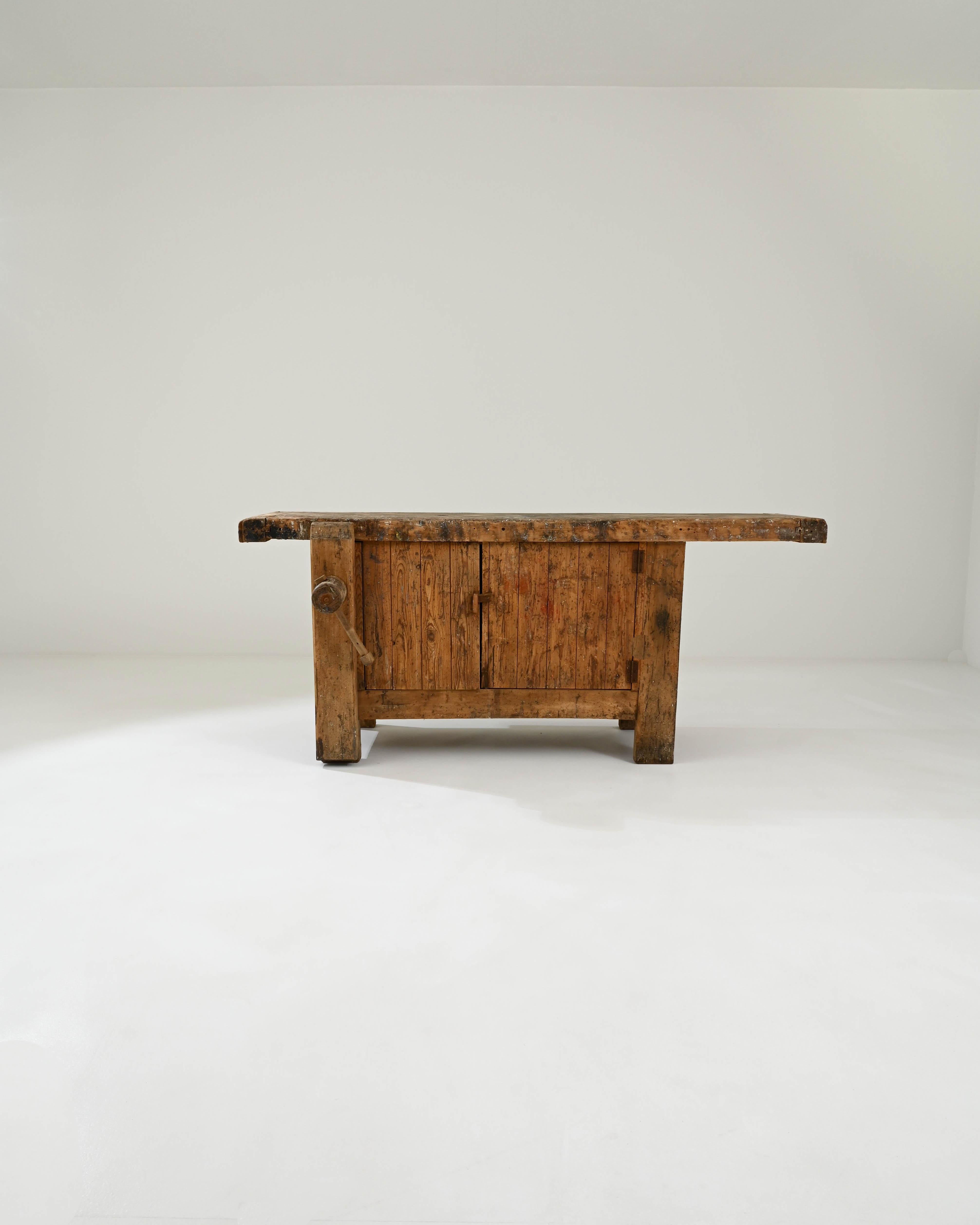 A wooden work table created in early 20th century Belgium. Hewn lumber compiled together in a sturdy and efficient construction, this giant of a work table greets one with a focused poise. A solid plank of hardwood, framed in by conjoining boards