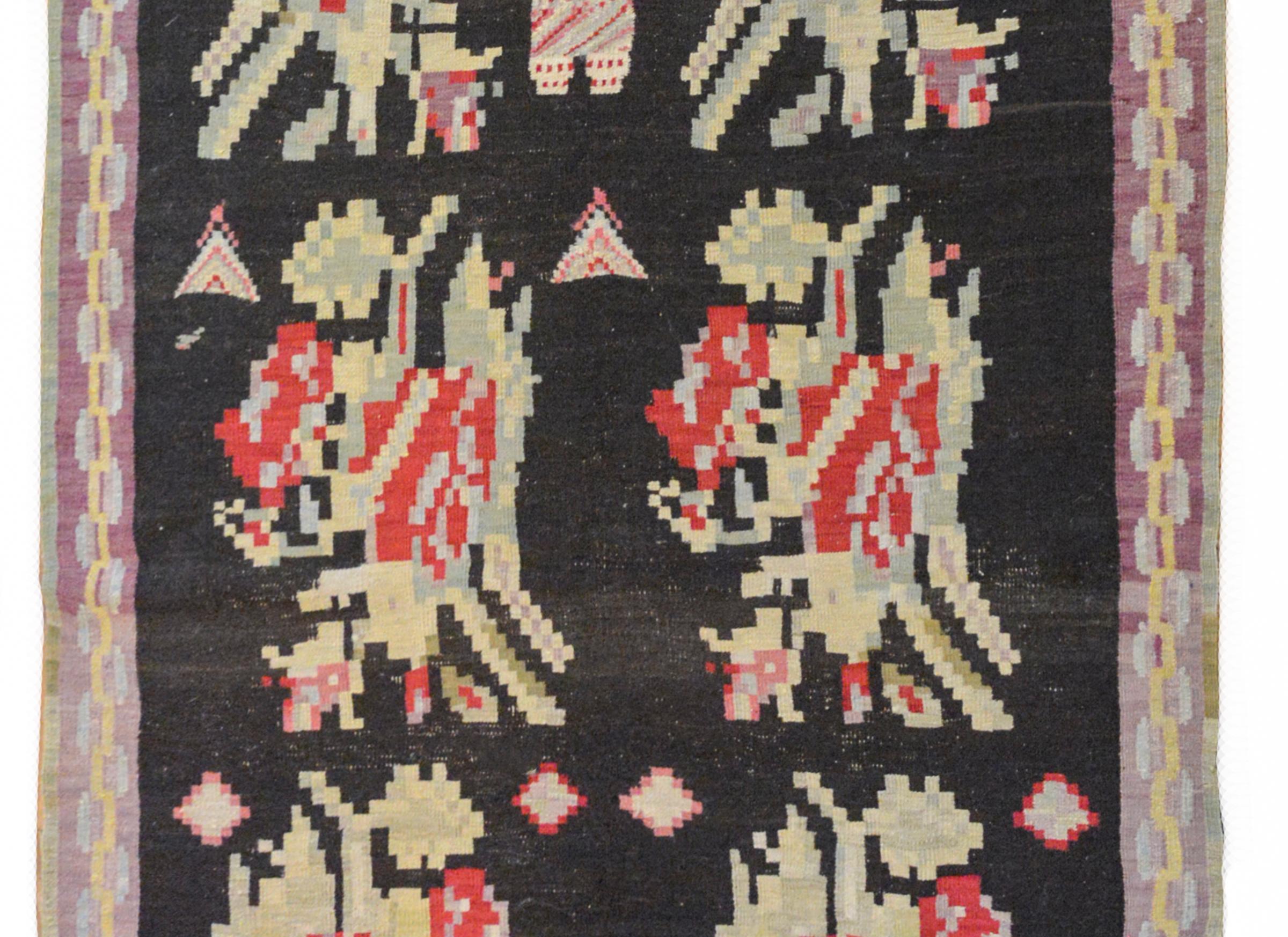 A wonderful early 20th century Turkish Bessarabian Kilim rug with ten stylized floral medallions woven in crimson, pink, pale indigo, pale green, and yellow against a black ground, and surrounded by a geometric pattered border.