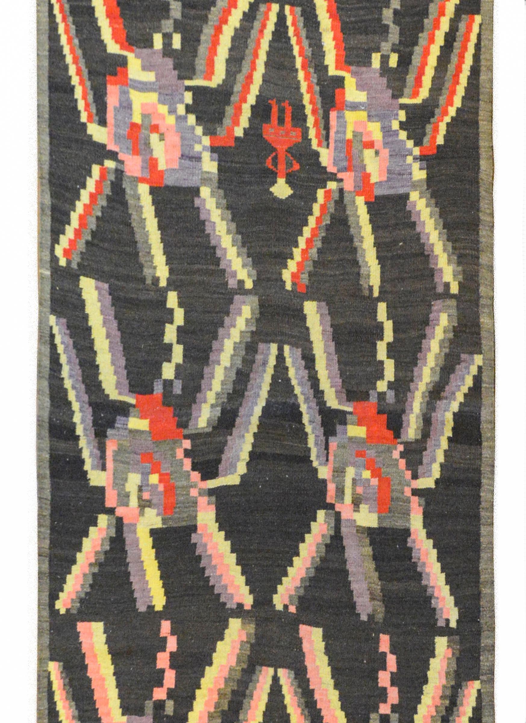 A wonderful early 20th century Turkish Bessarabian Kilim runner with twelve stylized abstract flowers woven in bright crimson, gold, and pale lavender, against a black ground with additional stylized flowers and people.