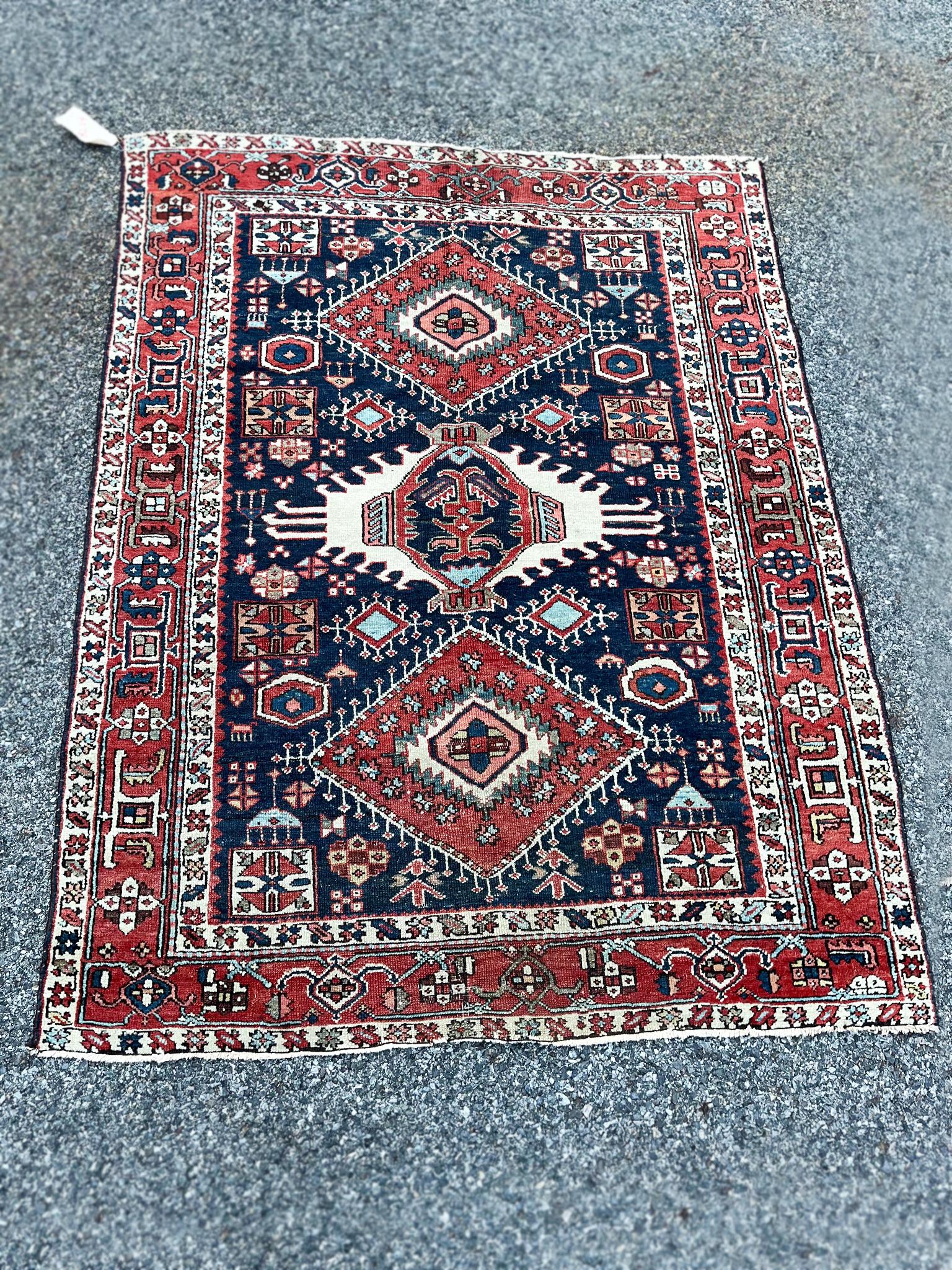 This Bibikabad rug was made in the early 20th century. It has a rich palette of red, blue, and ivory. The design features a central column of medallions floating in a blue field surrounded by floral, geometric forms and bounded by a series of