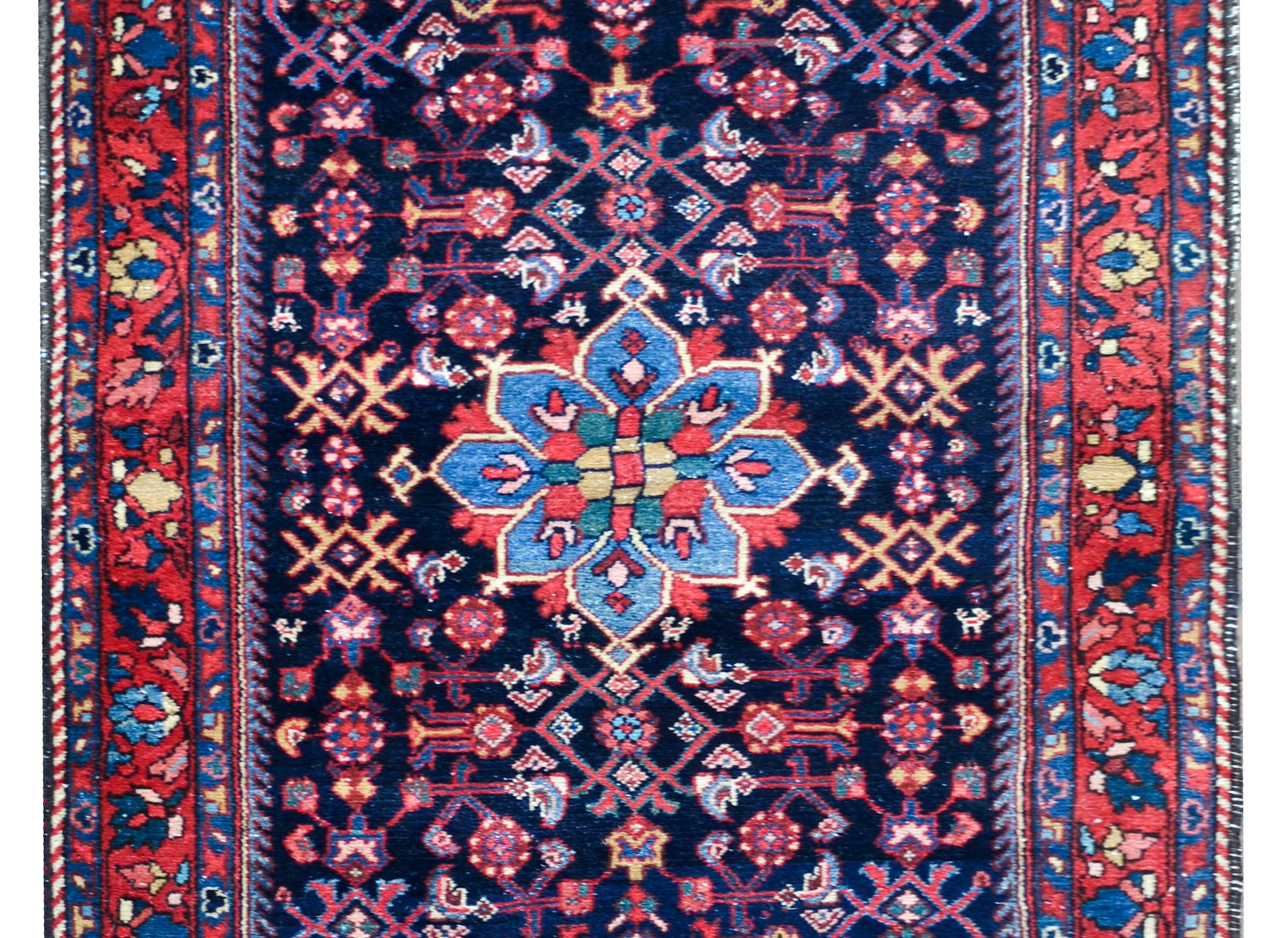 A striking early 20th century Persian Bibikibad rug with an all-over stylized floral and scrolling vine pattern woven in crimson, light and dark indigo, gold, and white against a dark indigo background. The border is wonderful with multiple large