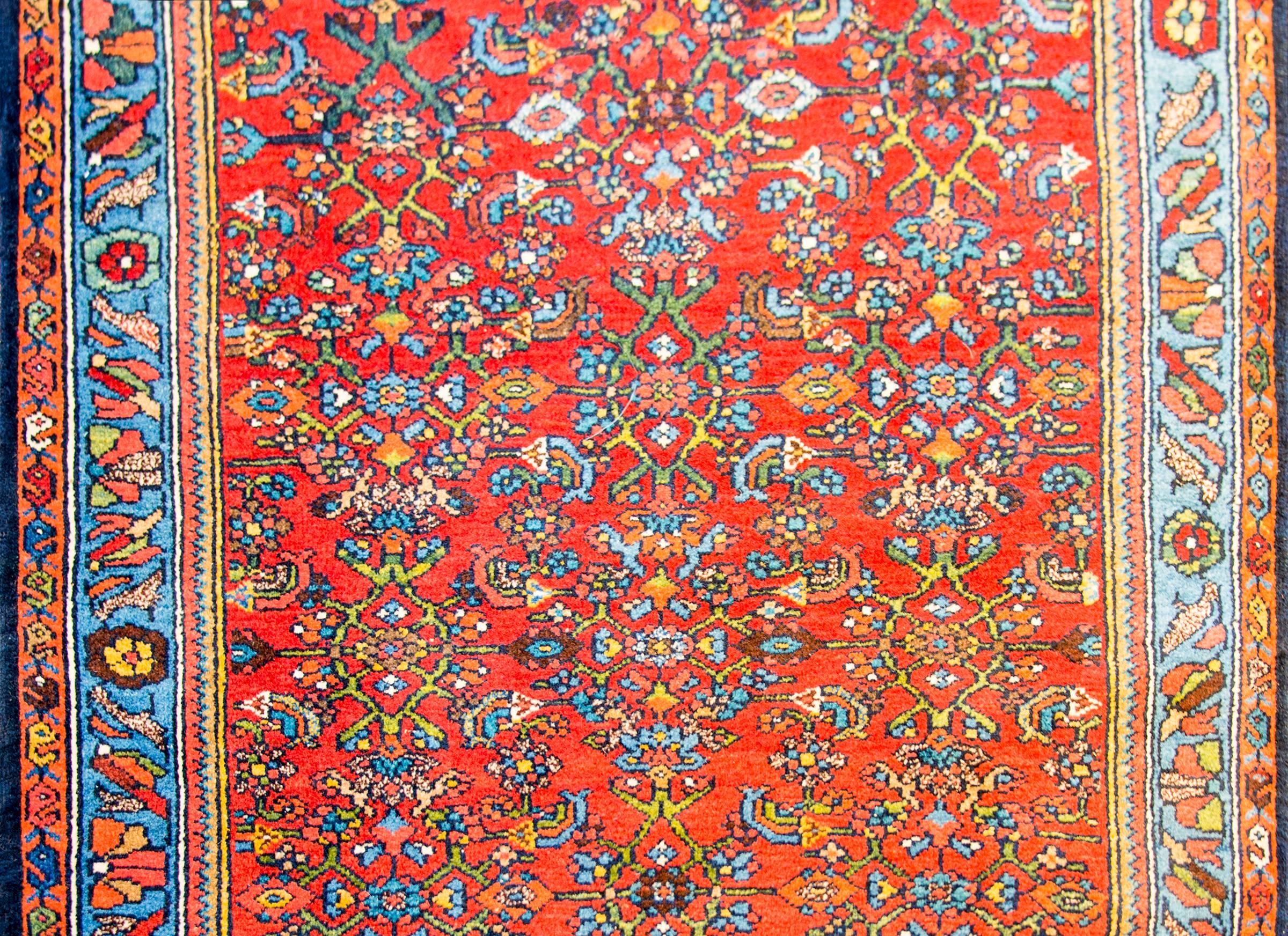 A wonderful early 20th century Persian Bidjar rug with an all-over lattice floral pattern woven in light and dark indigo, gold, green, and pink, on a beautiful crimson background. The border is amazing, composed of multiple floral patterned stripes.