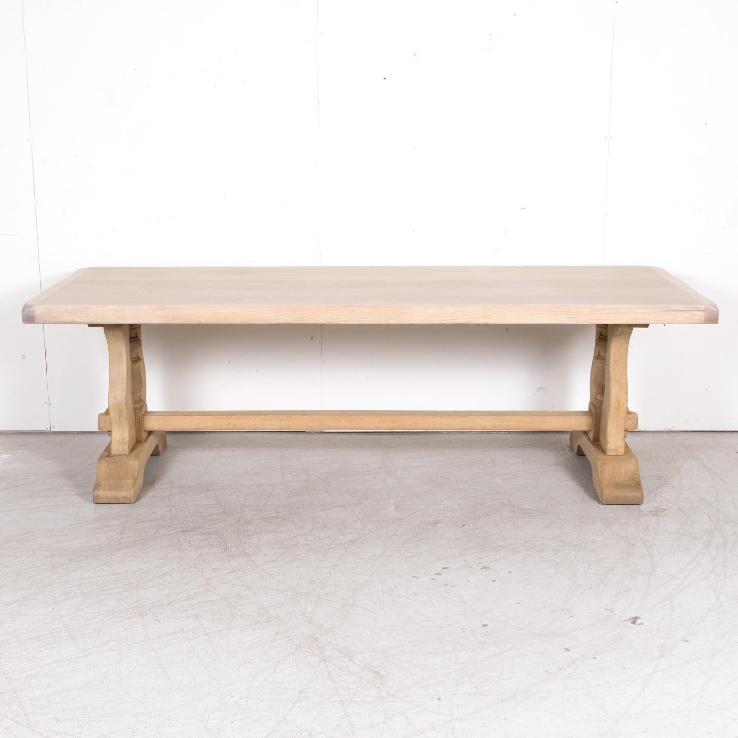 A handsome antique French monastery trestle dining table, circa 1920s, handcrafted with precision and care of solid oak by talented artisans in the picturesque seaside town of Étretat, nestled along Normandy's Alabaster coast. Having a rectangular